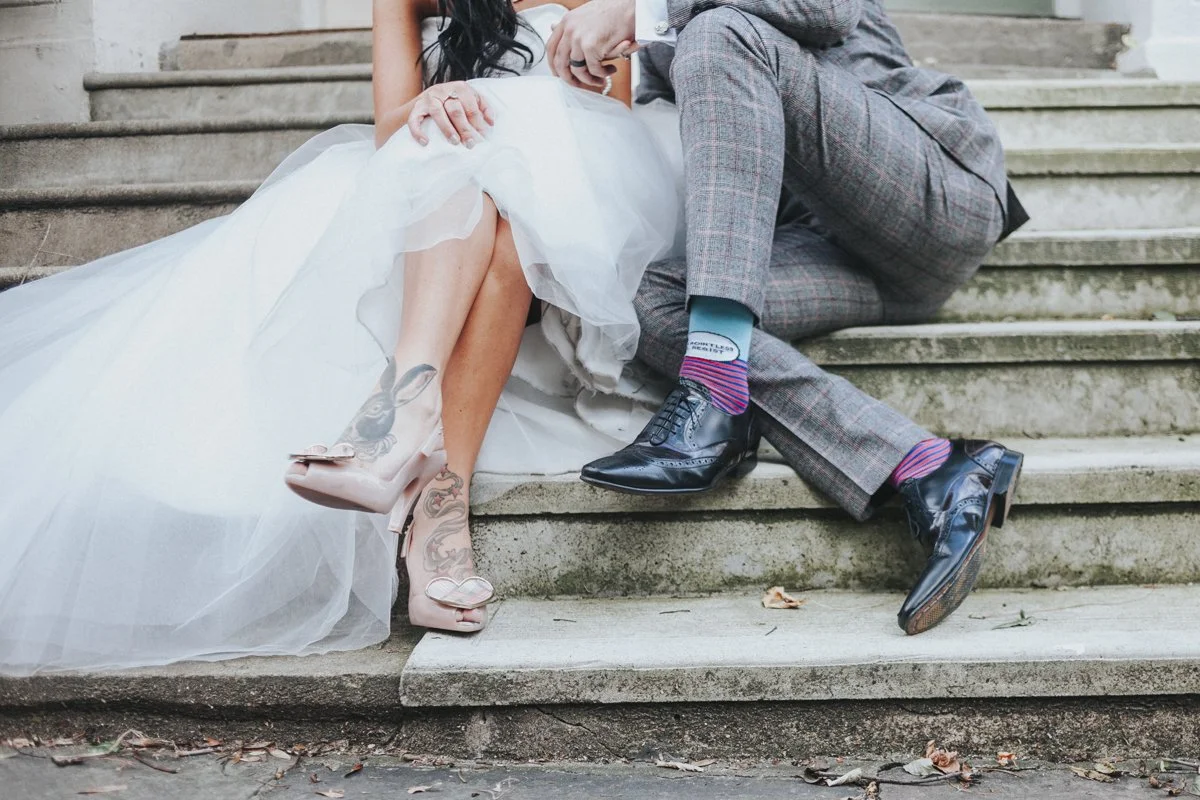 Just the Bride & Groom legs showing the grooms funny socks and the brides tattoos on her legs and feet. They are sitting down on a doorstep near Islington Town Hall Wedding Venue