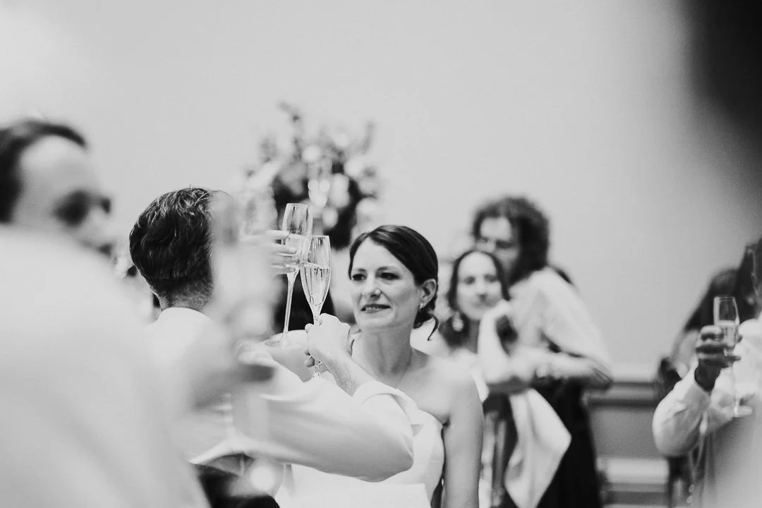 Bride cheersing glasses with Groom after speeches at the dinner table at a Hampton Court House Wedding.