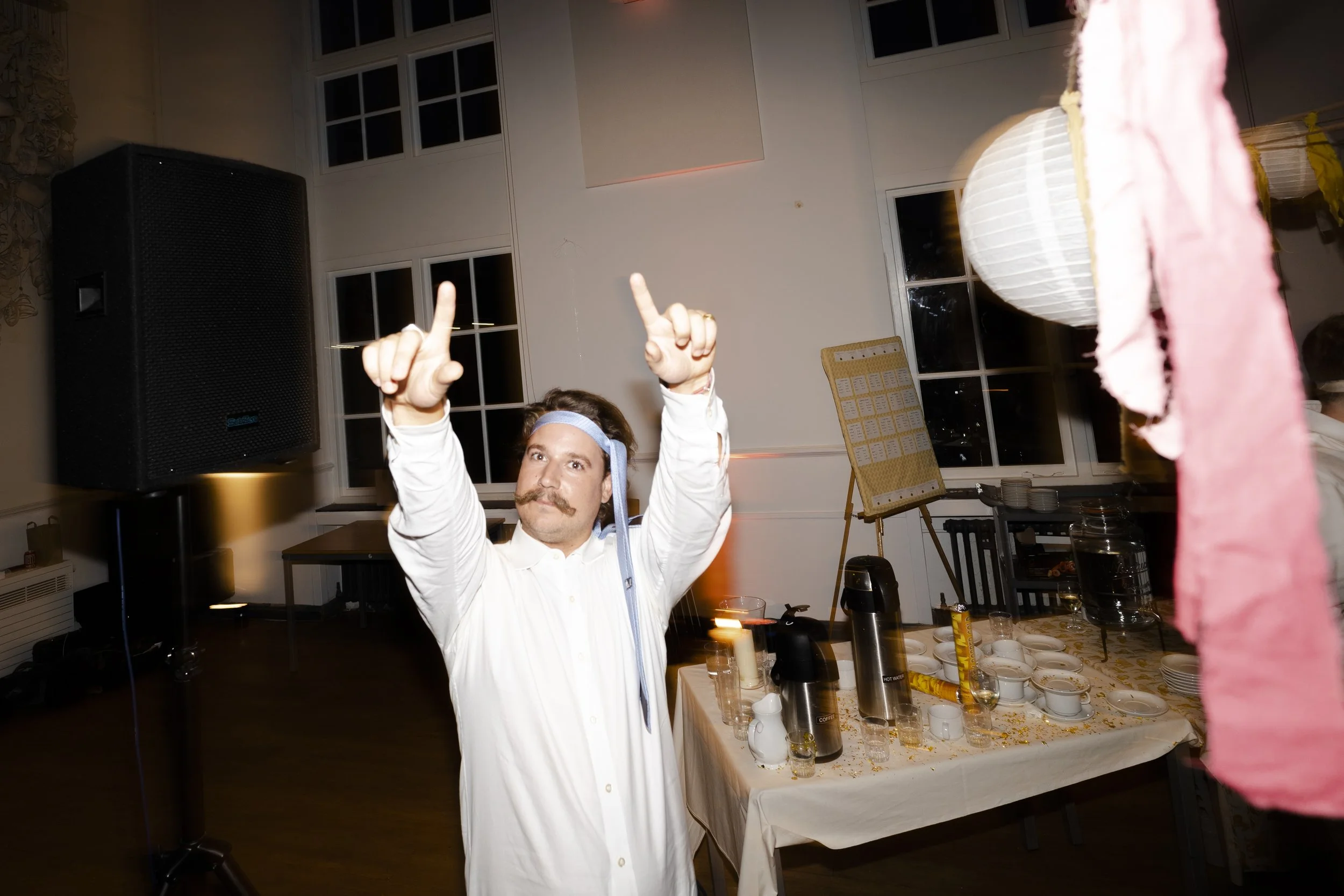 Guest with tie around his head points two fingers at the camera at a Highgate, London Wedding.