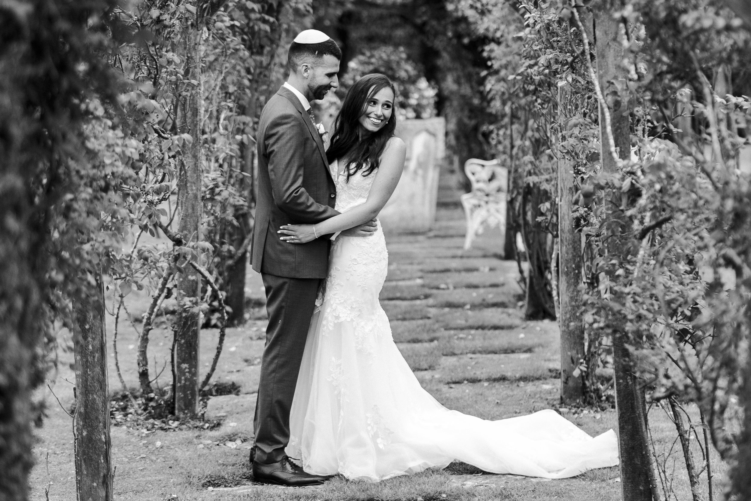 Couple posing in the orchard with the bride smiling at looking away at a Micklefield Hall Wedding