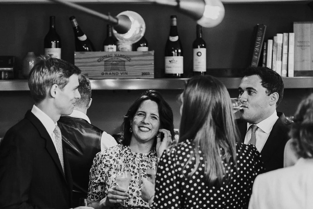 Guests chatting in the restaurant, with one female guest smiling and looking at the camera while playing with her earring at the Old Marylebone Town Hall Wedding.