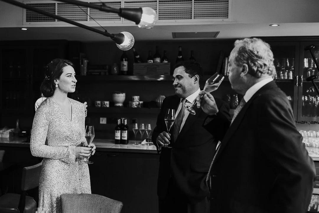 Bride talking to her brother and Groom's Father at a restaurant at the Old Marylebone Town Hall Wedding.