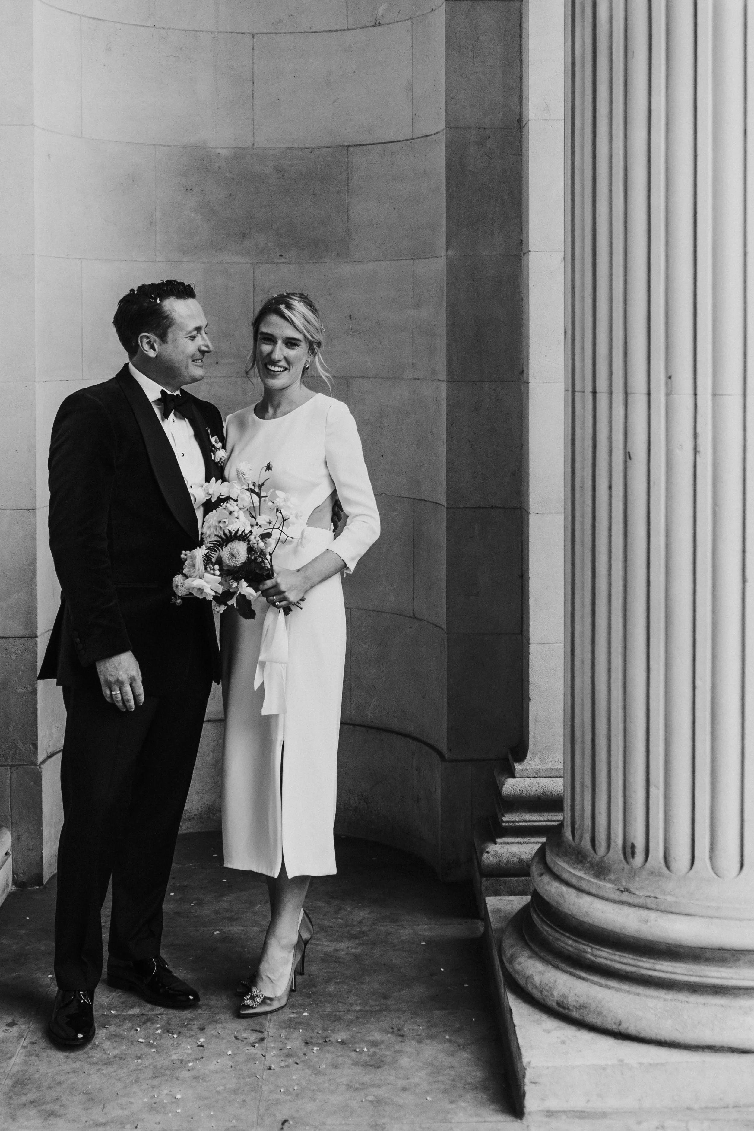 Bride & Groom posing for portraits next to the pillars at a Old Marylebone Town Hall Wedding