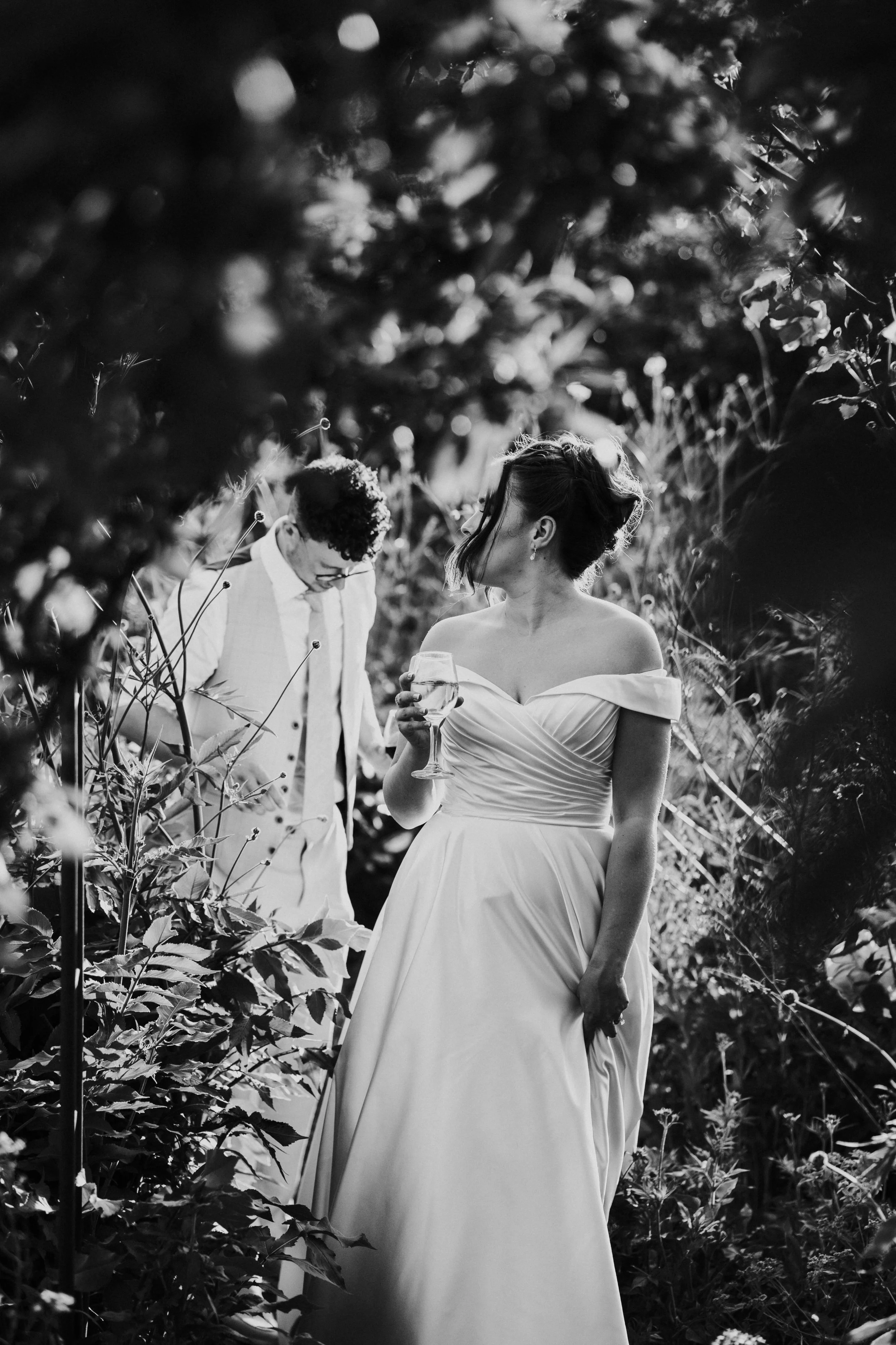Wedding couple walking through a flower garden with the bride ahead of the groom at a Worton Kitchen Garden, Oxfordshire Wedding.