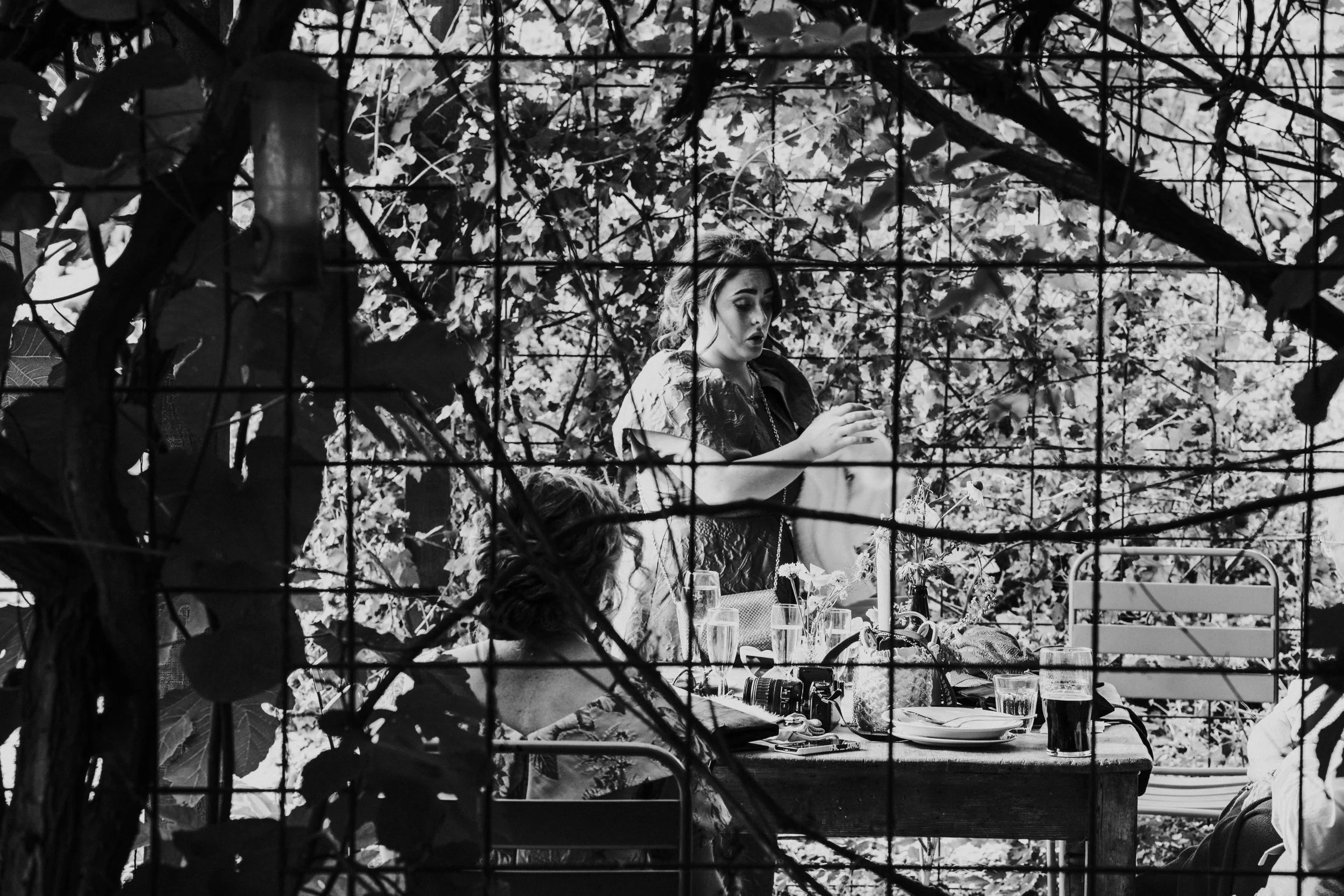 Bridesmaid through glass panels of the Greenhouse at a Worton Kitchen Garden, Oxfordshire Wedding.
