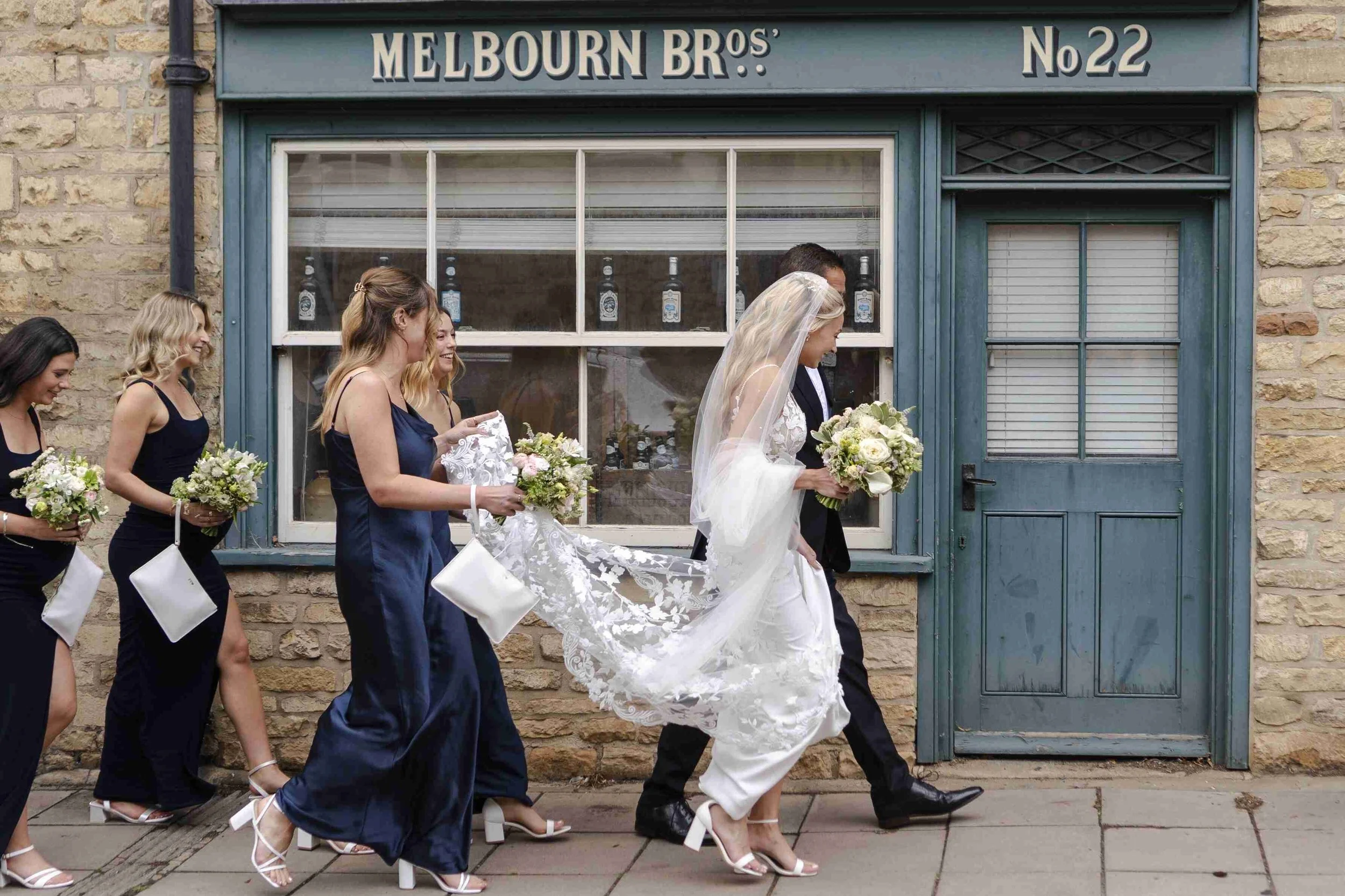 Bride passing a shop while walking down the street to the church before the Halfmoon Farm Wedding in Rutland