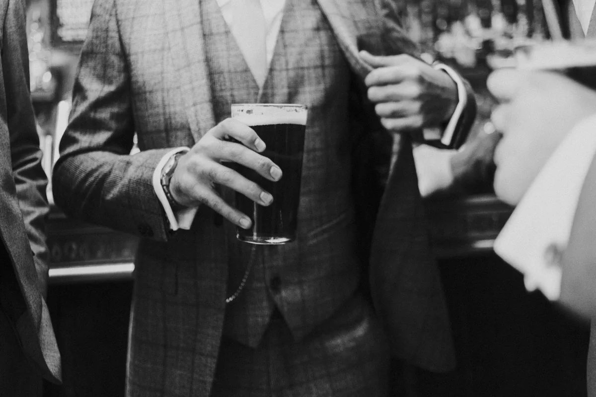 Groom holding a pint of Gusiness inside The Old Queens Head, Essex Road before his Islington Town Hall Wedding