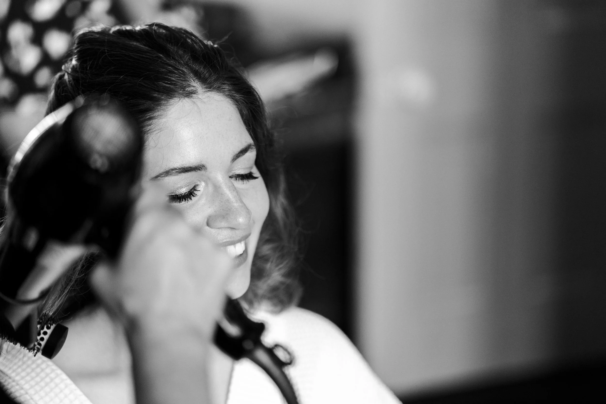 Bride smiling with her eyes closed getting her hair done sitting in the makeup chair at a Highgate, London Wedding