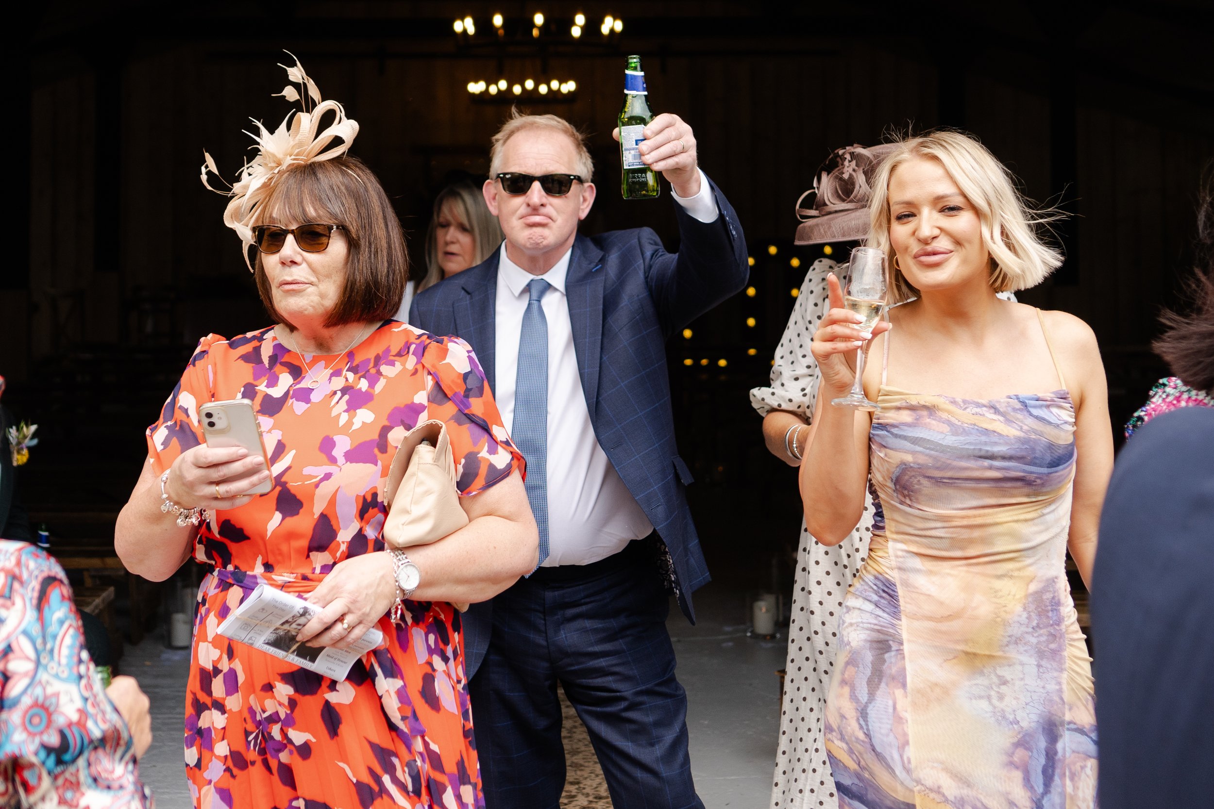Guests outside of ceremony barn looking at the camera and toasting at a rhyse farm wedding