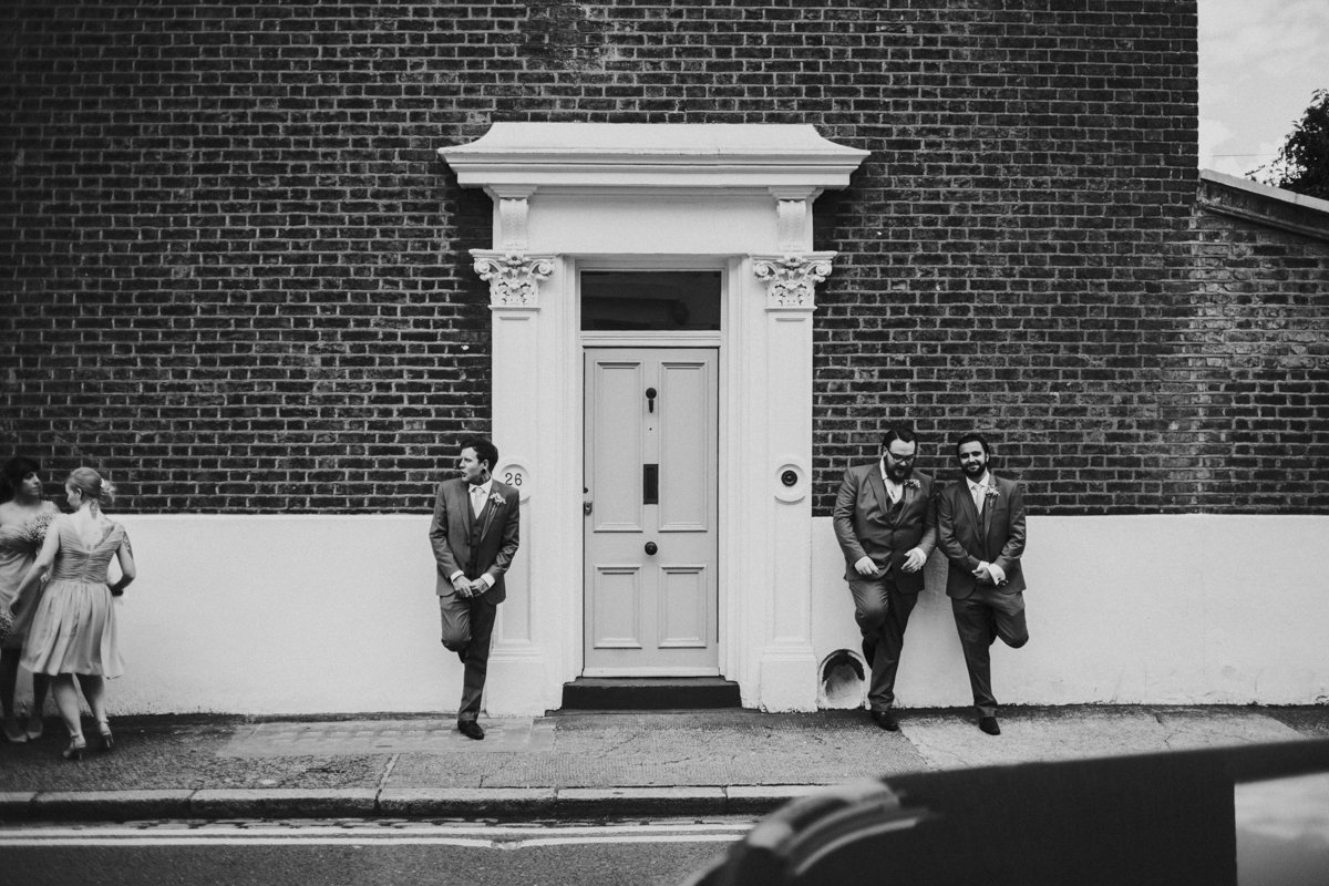 Groomsmen leaning against a wall looking cool near Islington Town Hall Wedding Venue