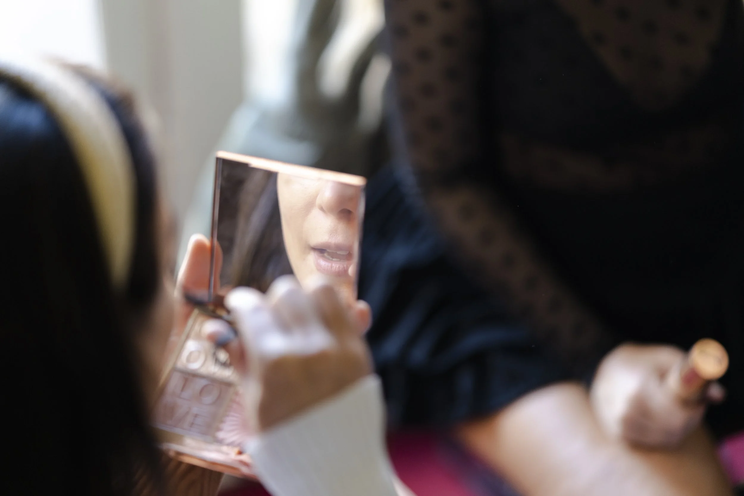 Bride looking at herself in a small pocket mirror at a Highgate, London Wedding