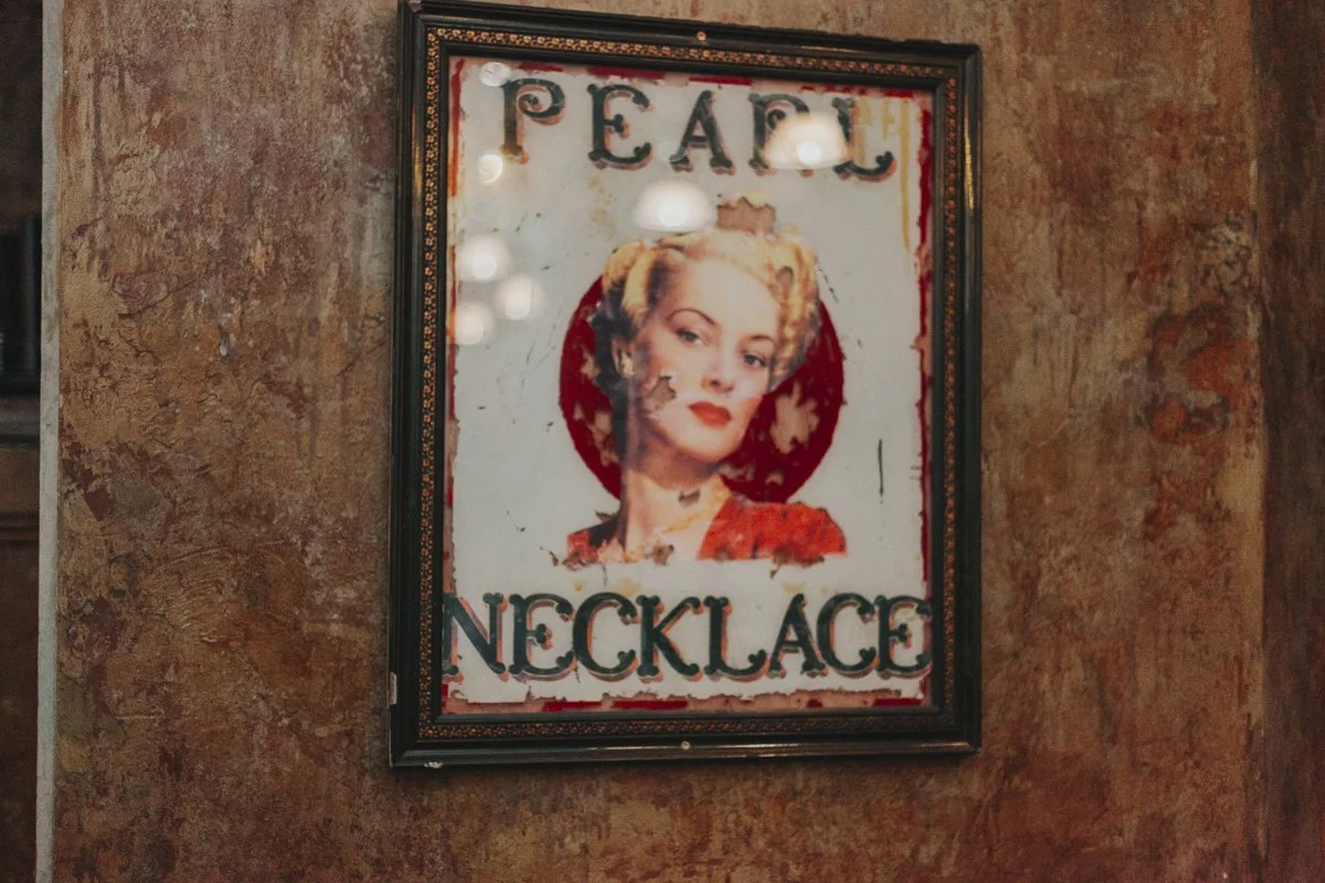 A old framed image of a woman with the wording Pearl Necklace at the iconic The Old Queens Head pub, Essex Road, Islington for a London Wedding