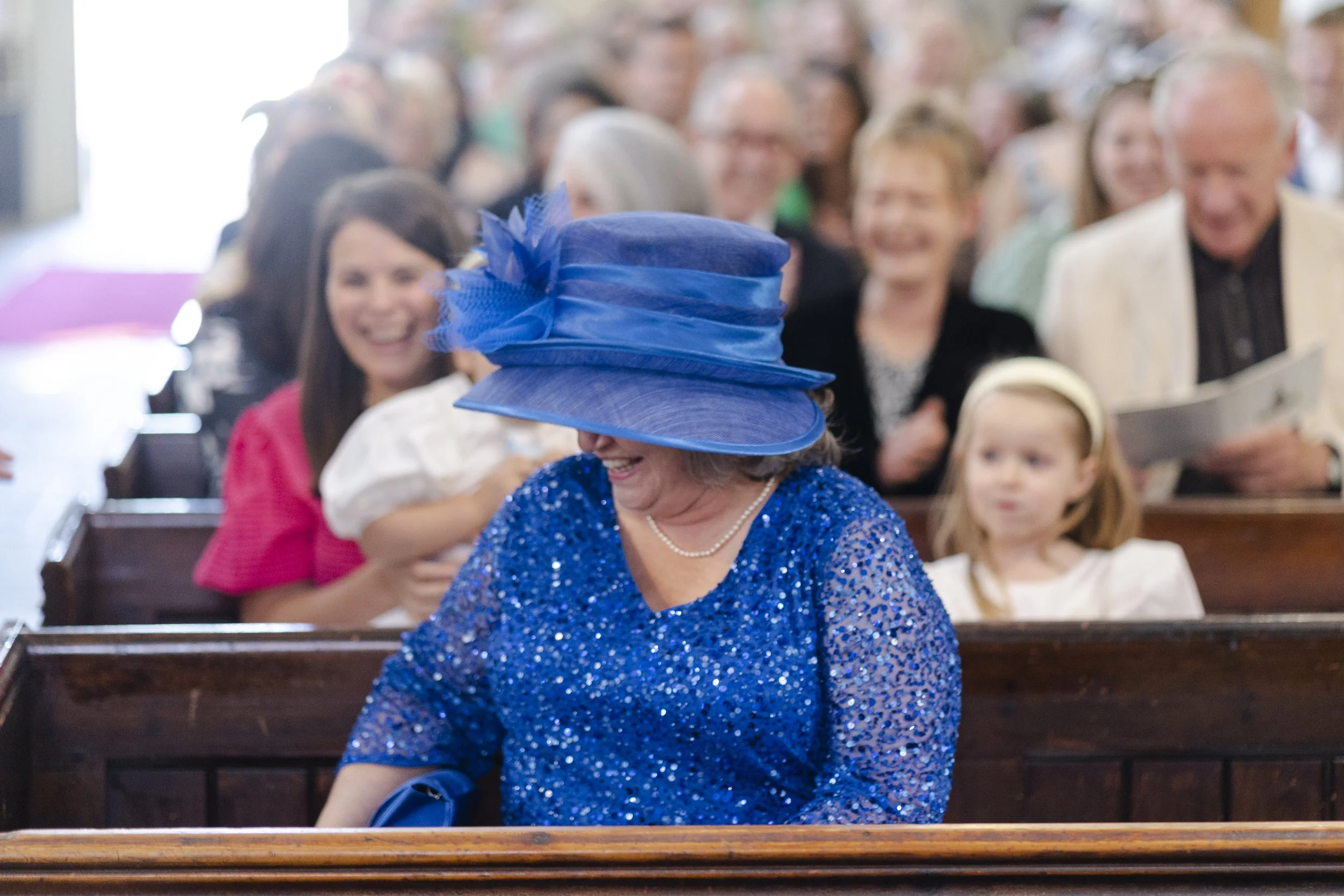 Mother of the bride, sitting in the front pew wearing a large blue hat at a Highgate, London Wedding