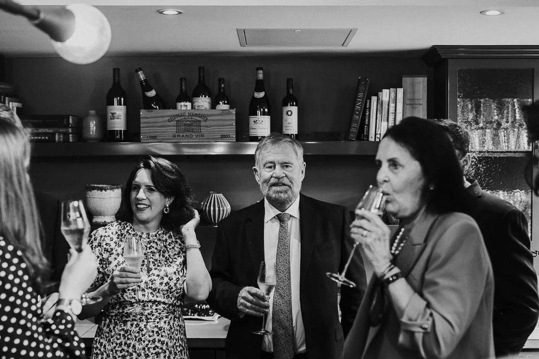 Wedding guests standing around chatting while the Bride's Father stares and looks at the camera, at a restaurant near the Old Marylebone Town Hall Wedding.