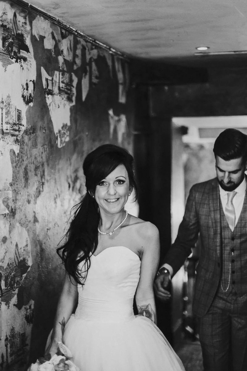 Bride walking in front of groom in the hallway to the wedding reception at the iconic The Old Queens Head, Essex Road, Islington for a London Wedding