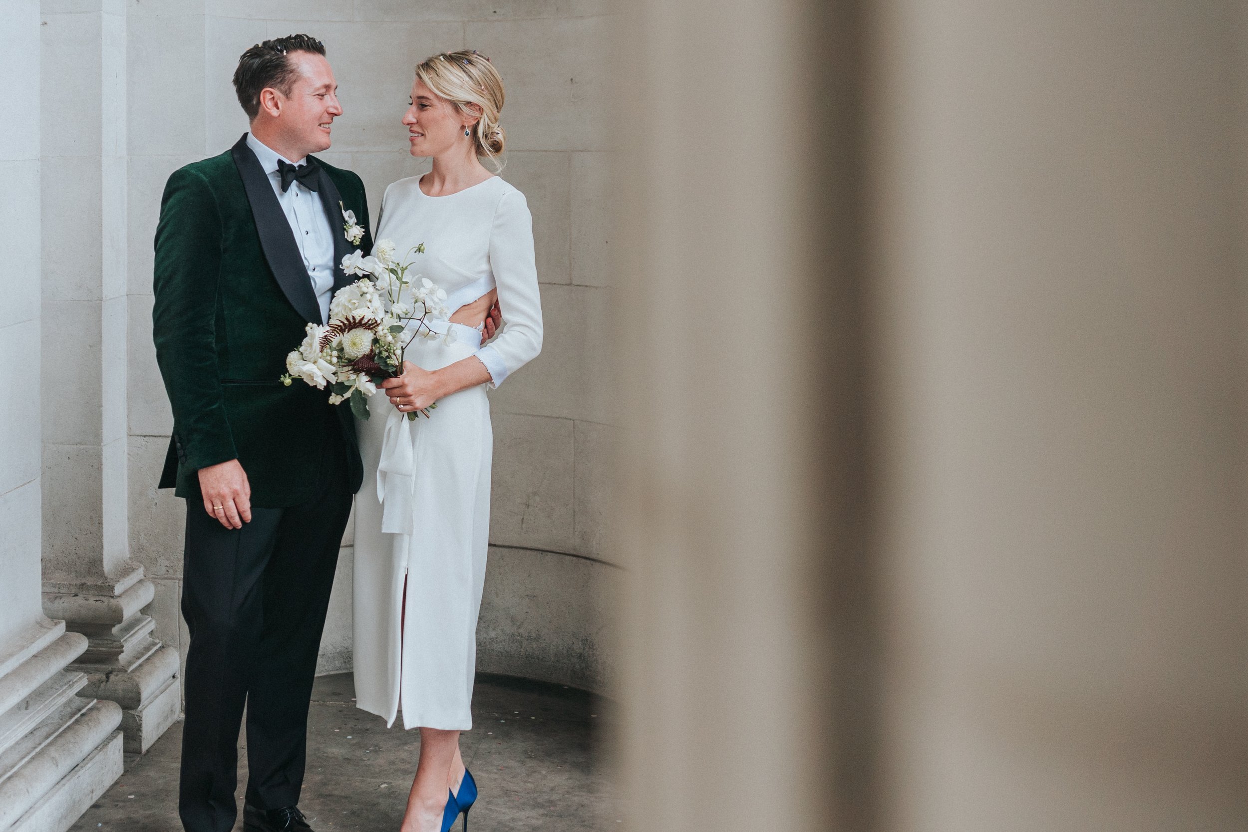 Wedding couple posing for portraits next to the pillars at a Old Marylebone Town Hall Wedding