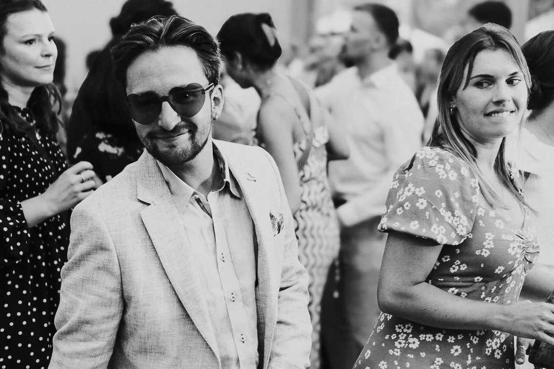 A guest wearing Heart-shaped sunglasses looking and smiling at the camera on the dancefloor at a Hampton Court House Wedding.