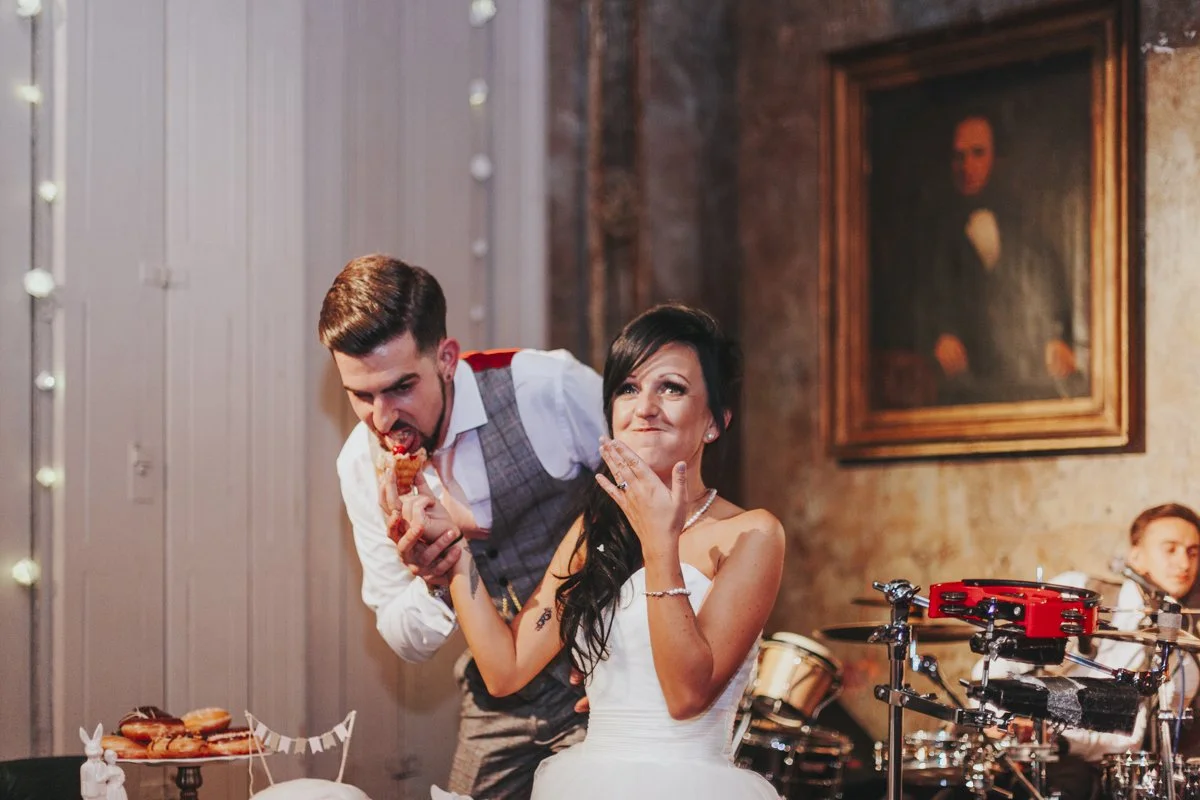 Bride & Groom on the stage at their wedding reception feeding each other cake at the iconic The Old Queens Head, Essex Road, Islington at a London Wedding