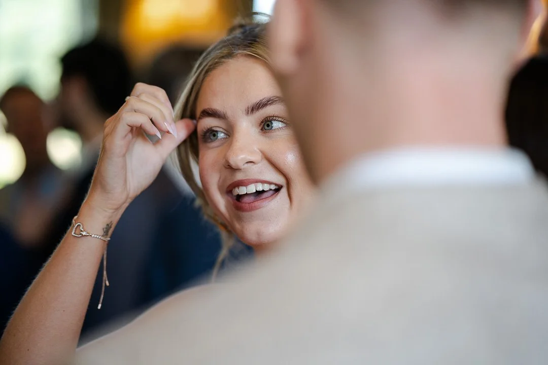 Guest before the ceremony smiling and moving her hair out of their face at a Hampton Court House Wedding