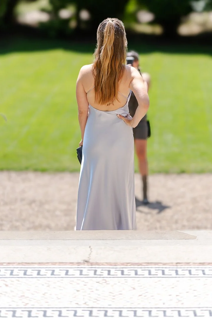 A guest posing on the front steps while another guest takes her portrait at a Hampton Court House Wedding
