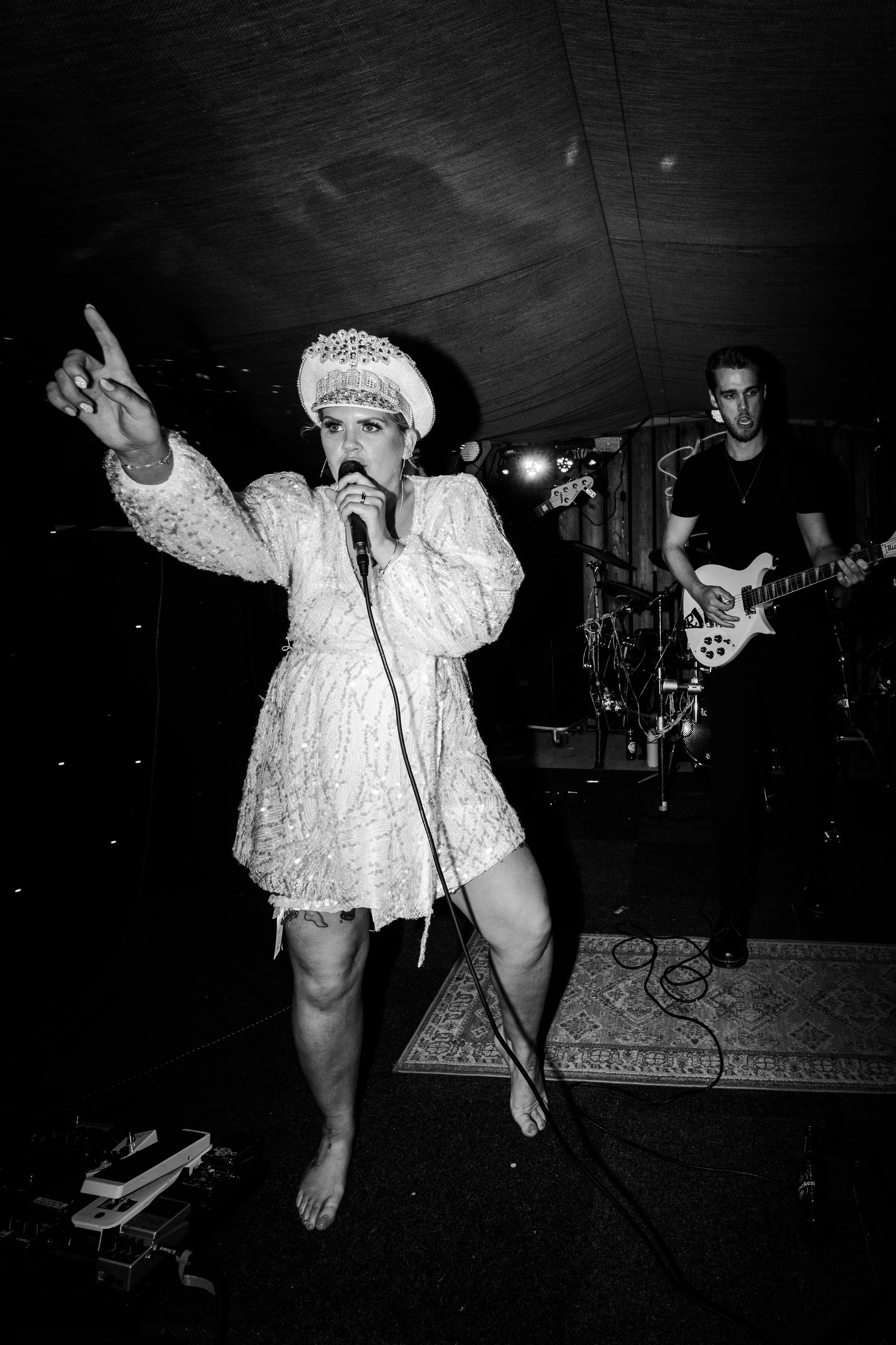 Bride on stage wearing a large hat singing with a microphone at a rhyse farm wedding