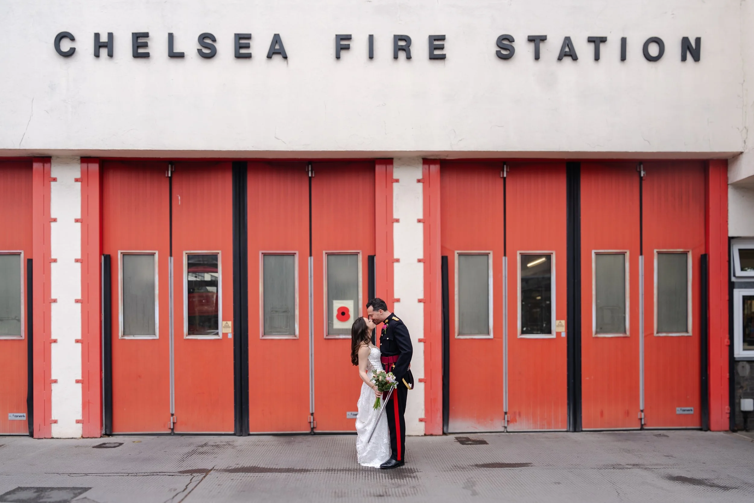 A bride and groom gaze at each other by Chelsea Fire Station's red doors—perfect for any wedding photography portfolio.