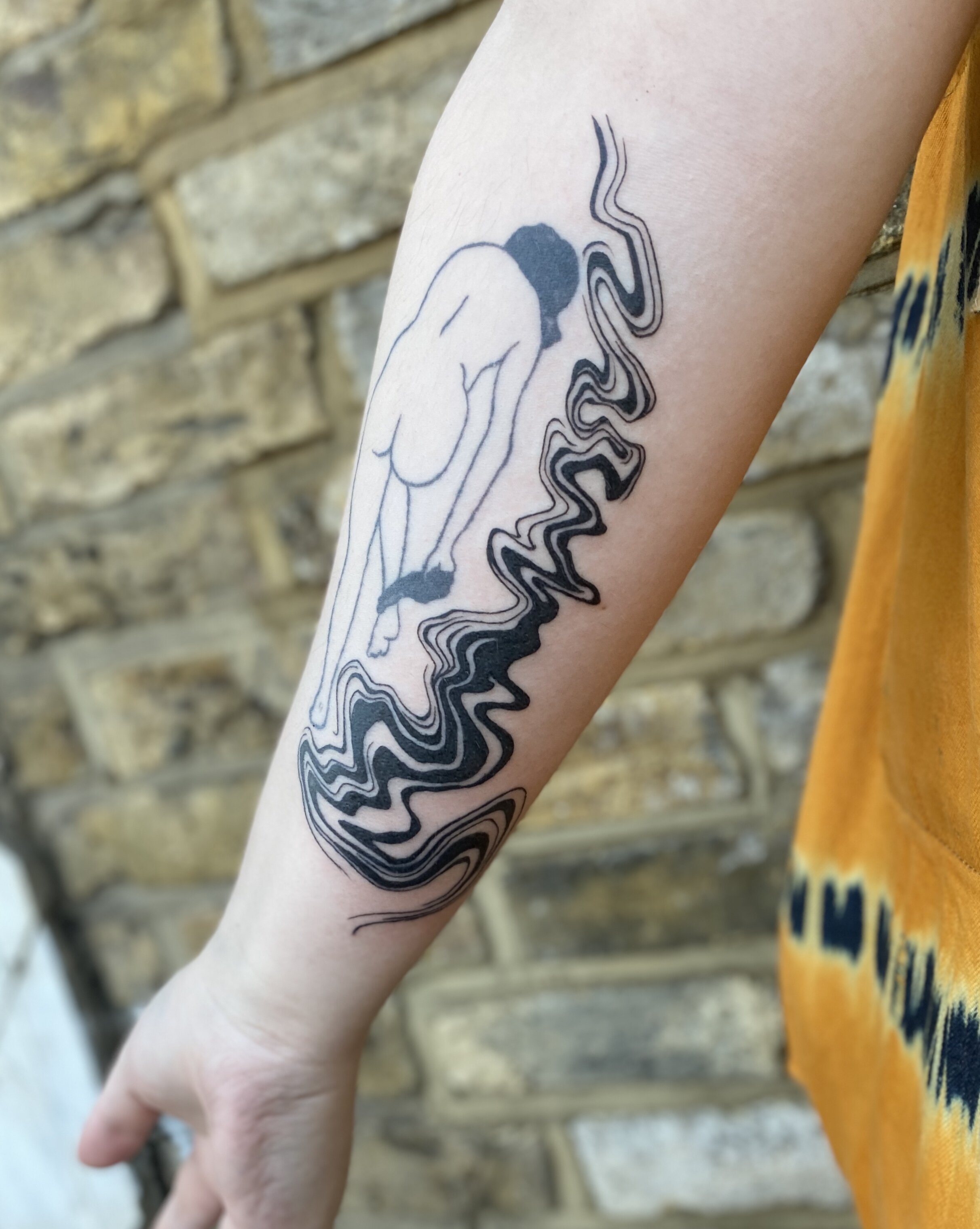 Forearm tattoo featuring a minimalistic line drawing of a person bending with abstract wavy lines, against a blurred brick background.