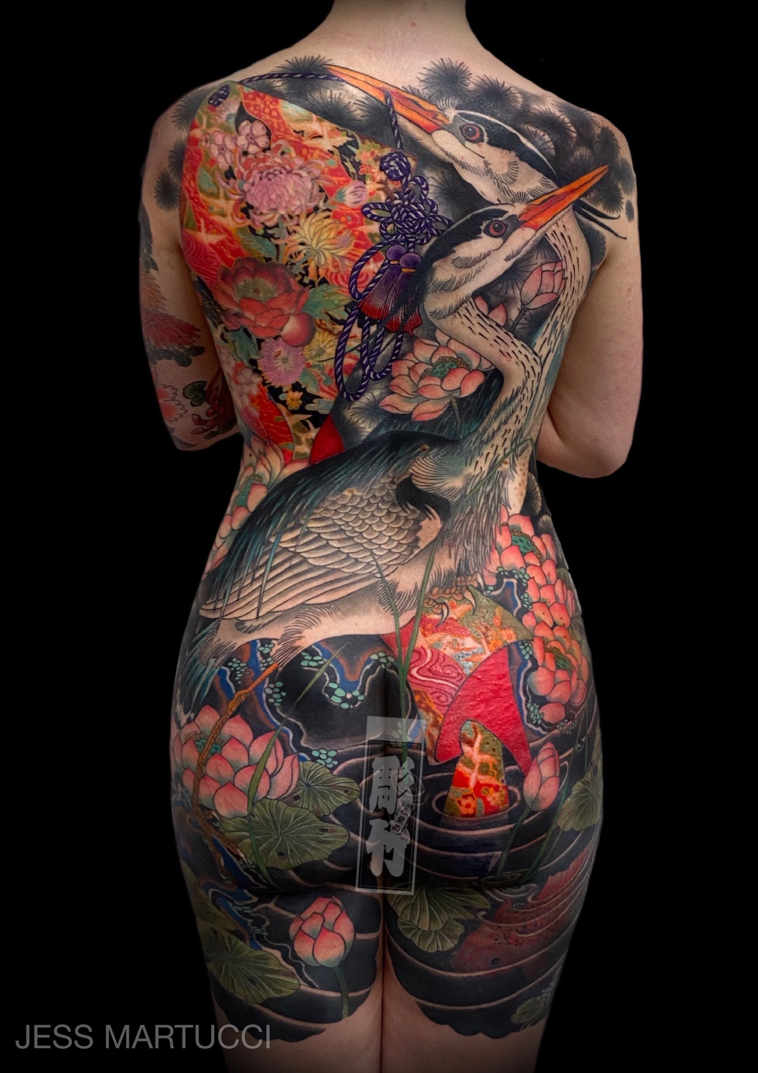 Full back tattoo featuring intricate herons, flowers, and koi fish with vibrant colors and detailed patterns.