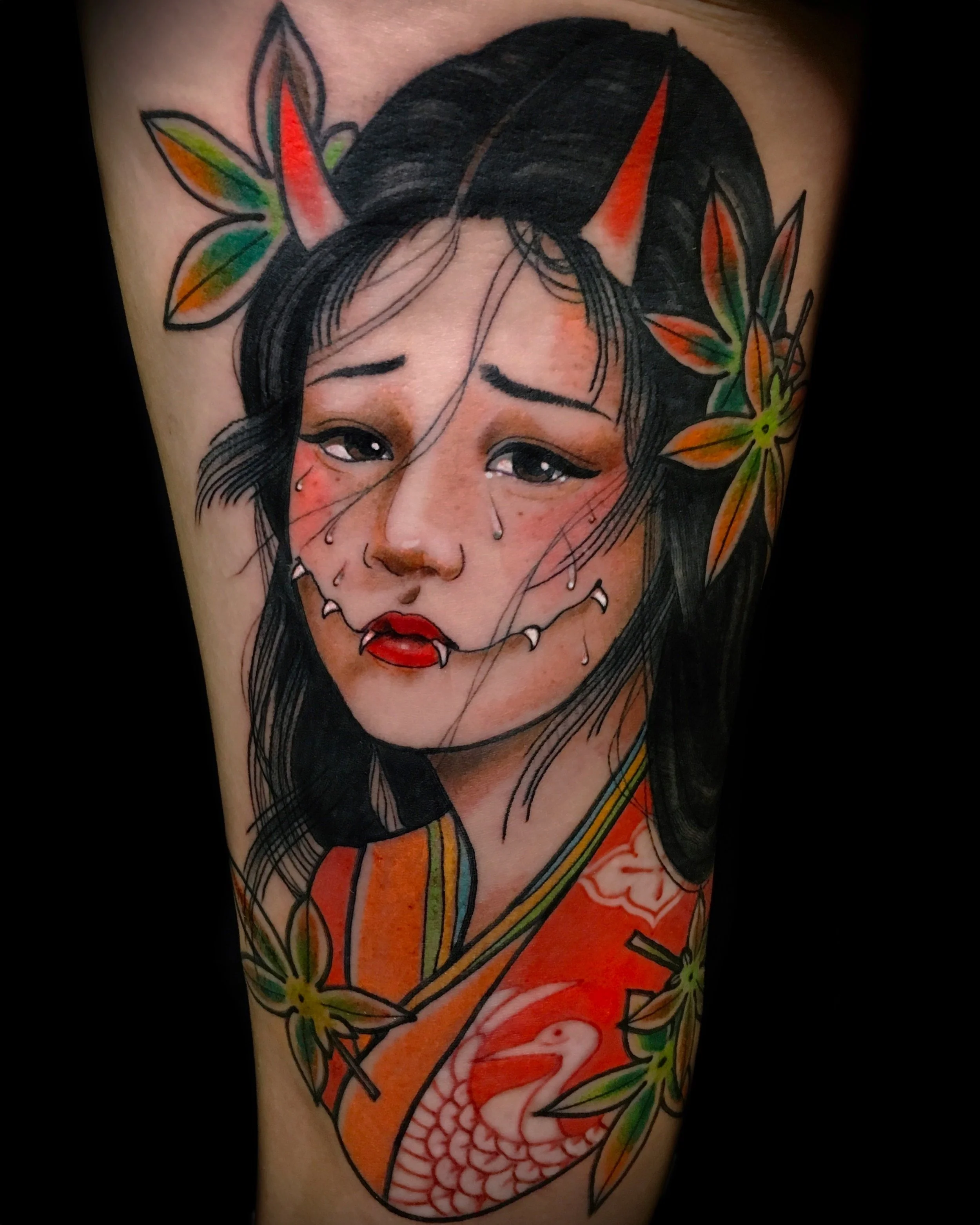 Tattoo of a woman with demon horns, wearing a traditional outfit with floral and crane designs.