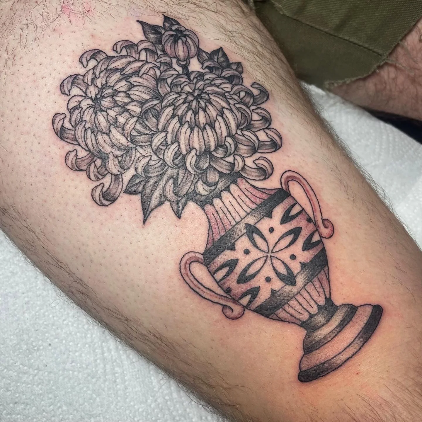 Tattoo of a decorative vase with ornate floral design on skin