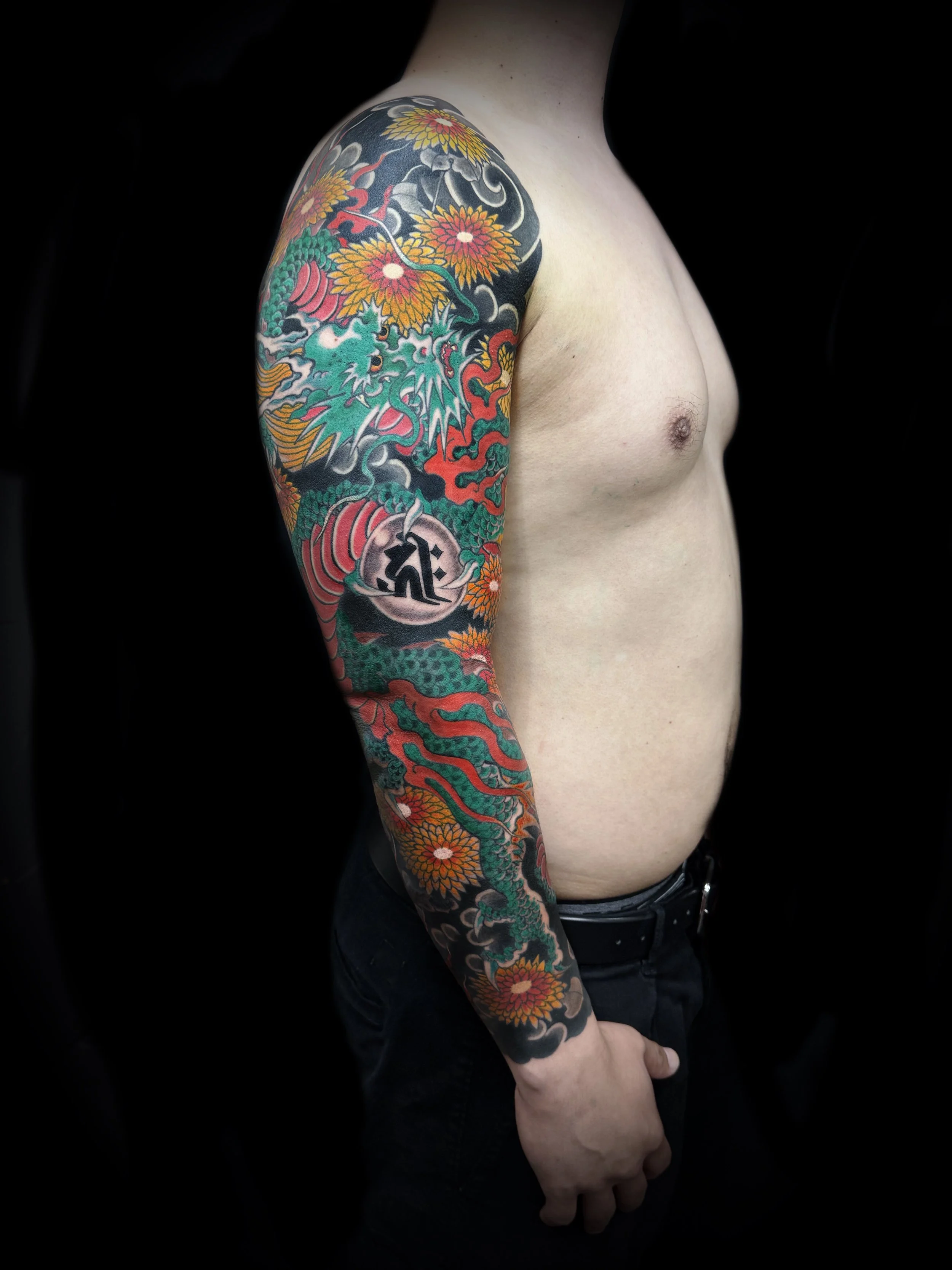 Colorful full sleeve dragon tattoo on a person's arm.
