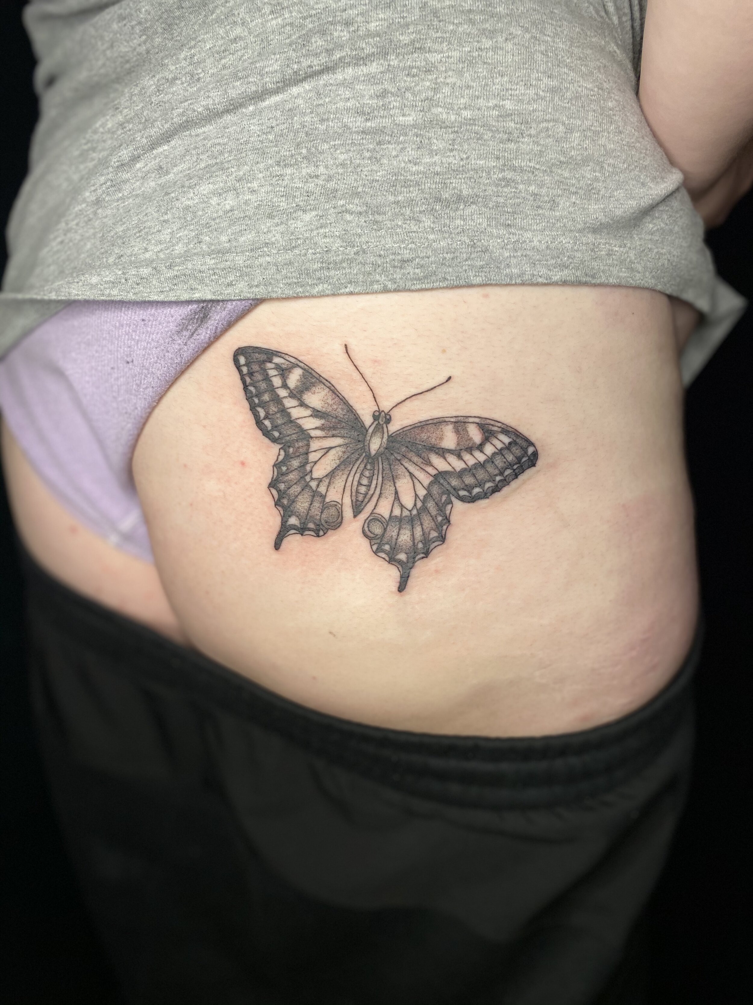 Butterfly tattoo on person's hip