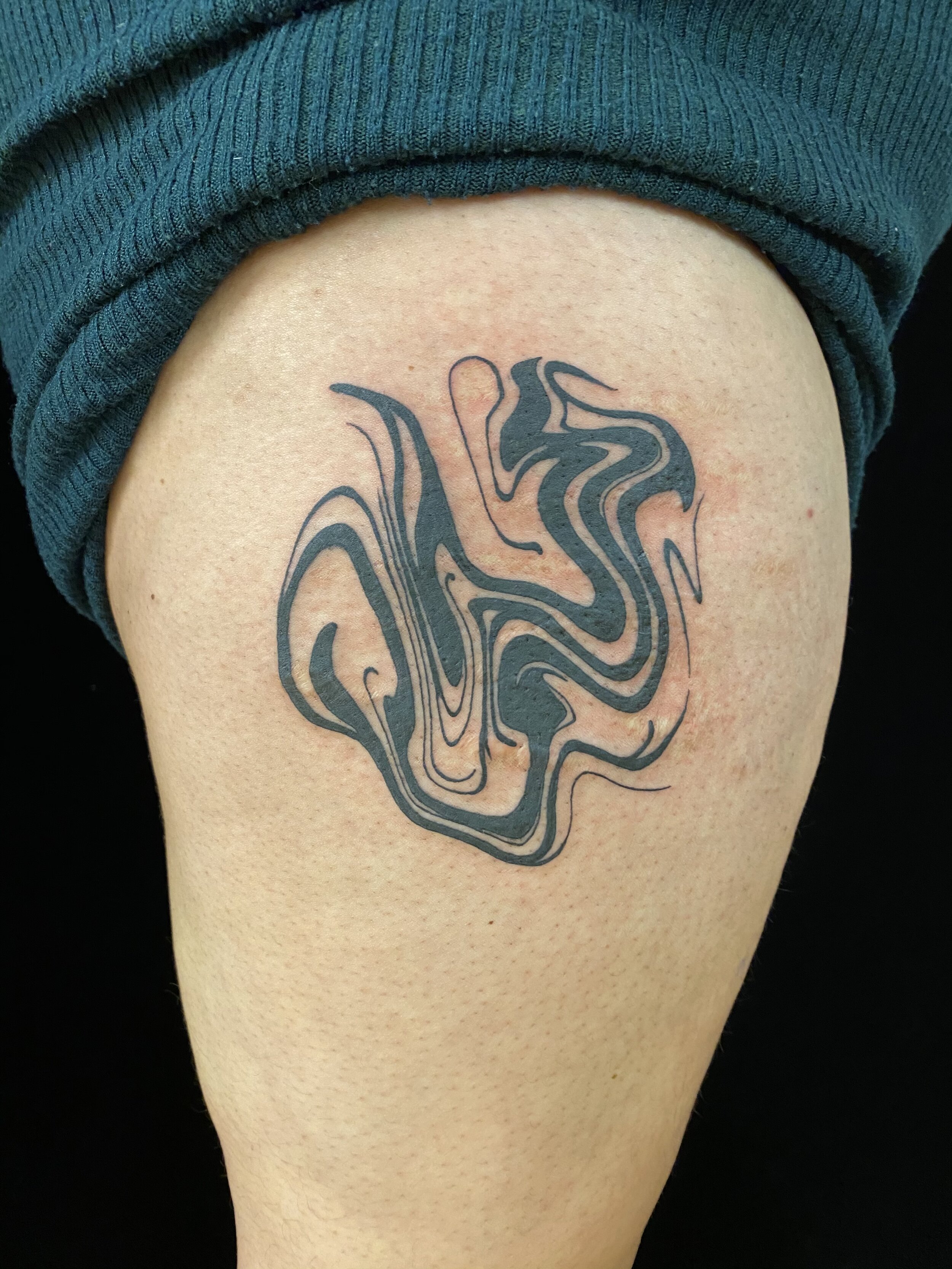 Abstract black swirl tattoo on upper thigh