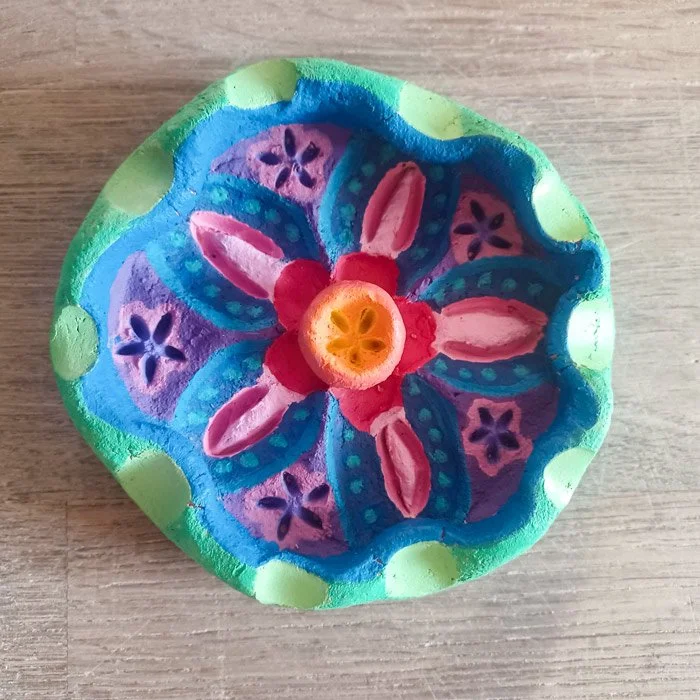 Bunte handbemalte Keramikschale mit floralem Blumenmuster auf Holztisch