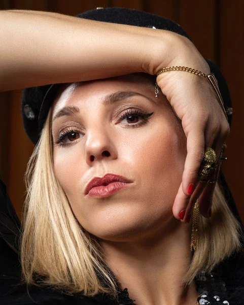 Photograph of Tamara Shlesinger with her hand around the top of her face