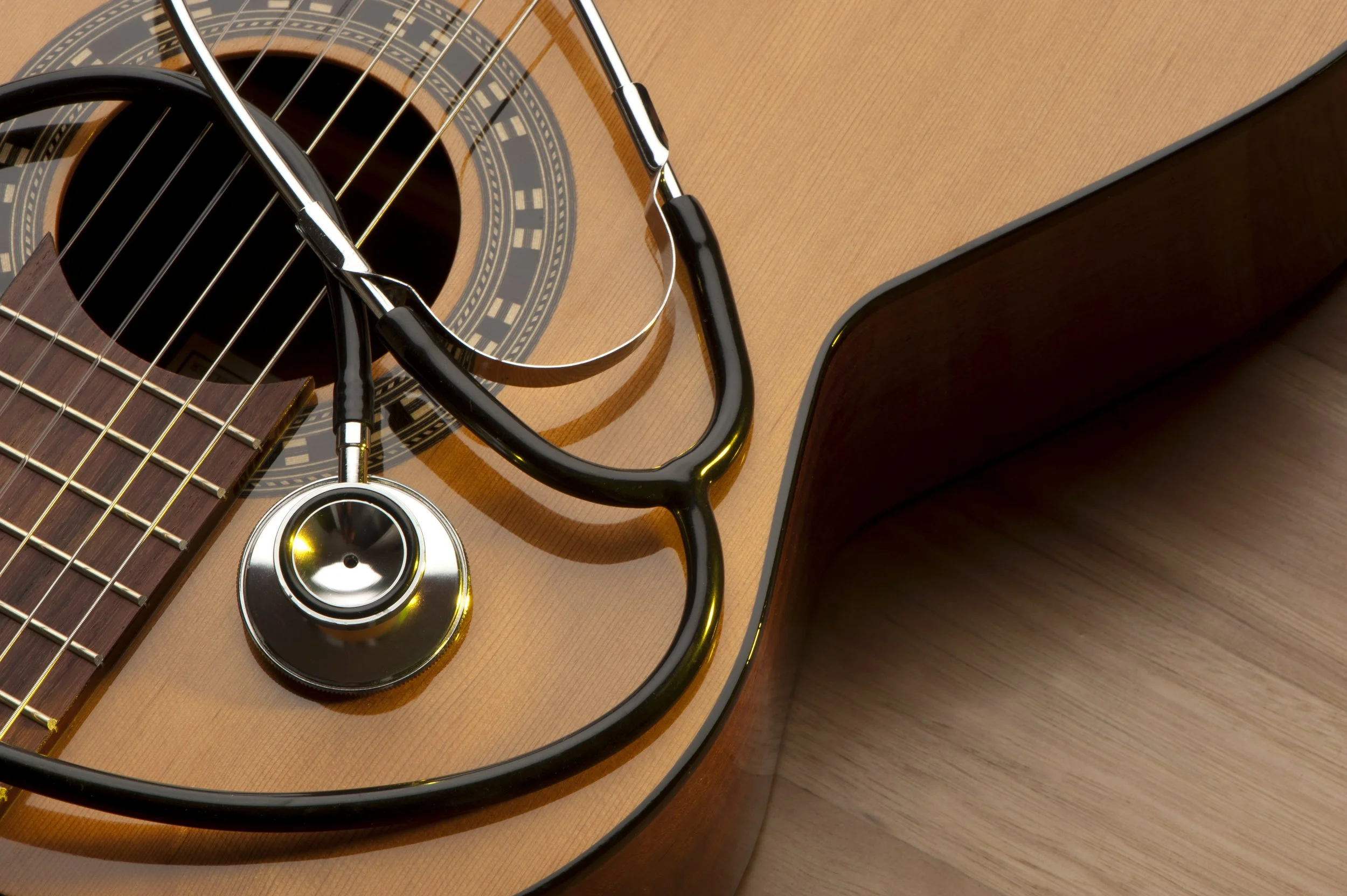 Acoustic guitar with stethoscope promoting expert guitar repairs and maintenance in College Station, Texas