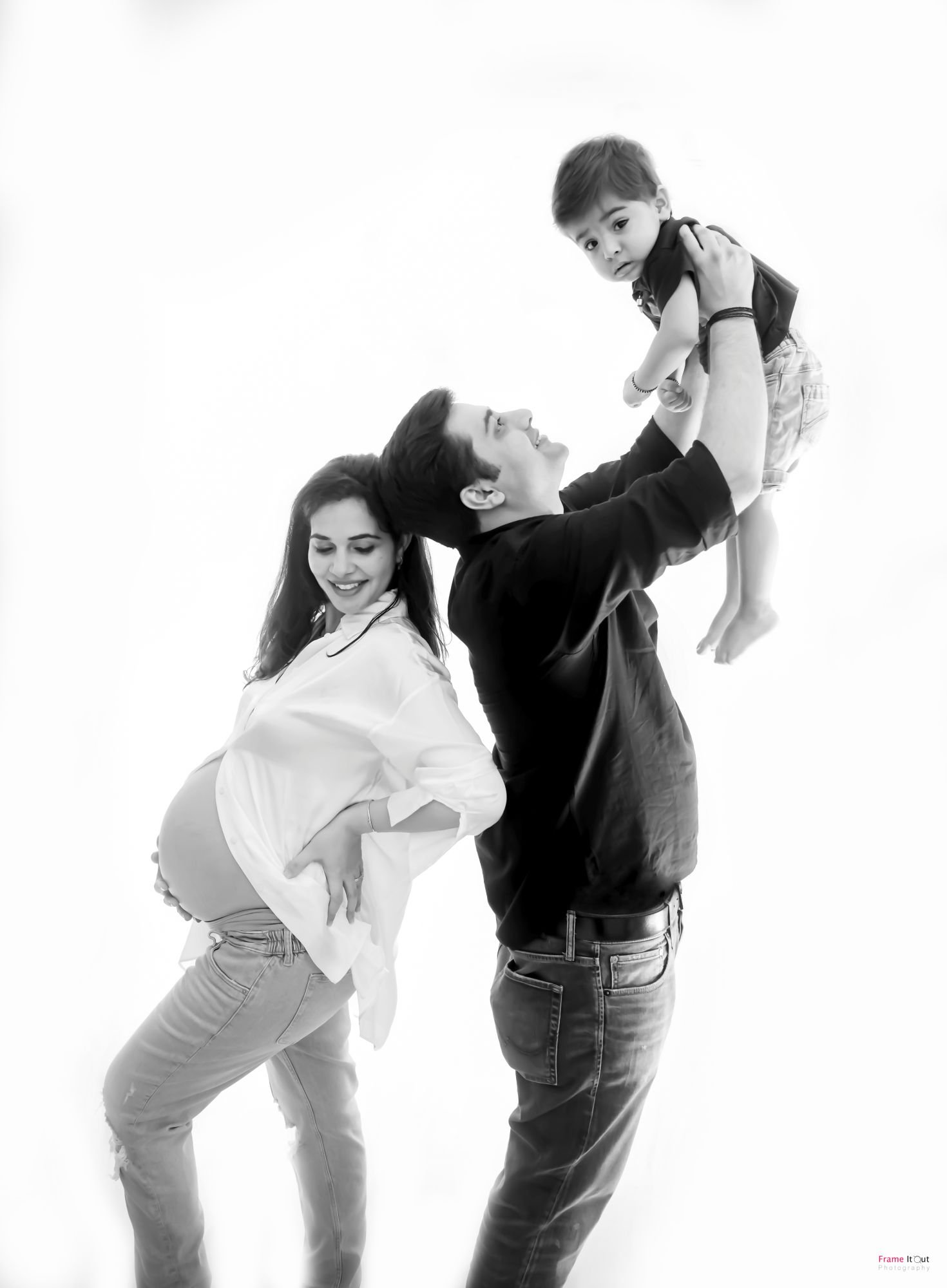 Dramatic black and white shot of pregnant mother looking over shoulder with Dad and elder child