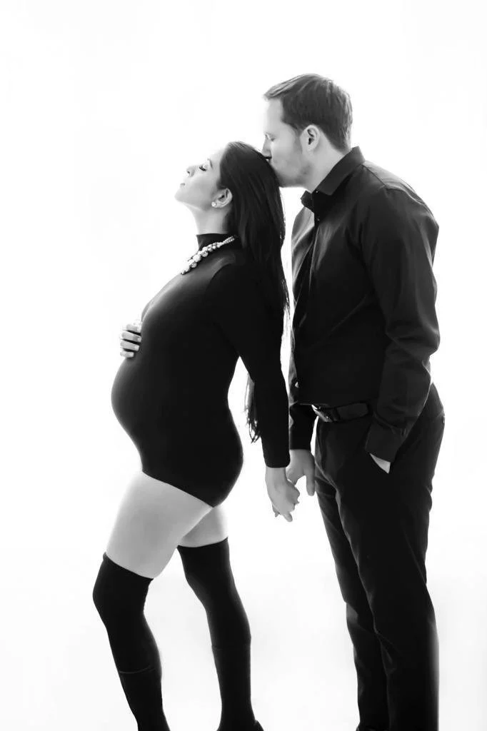Black and white maternity portrait of couple holding hands in a classic pose
