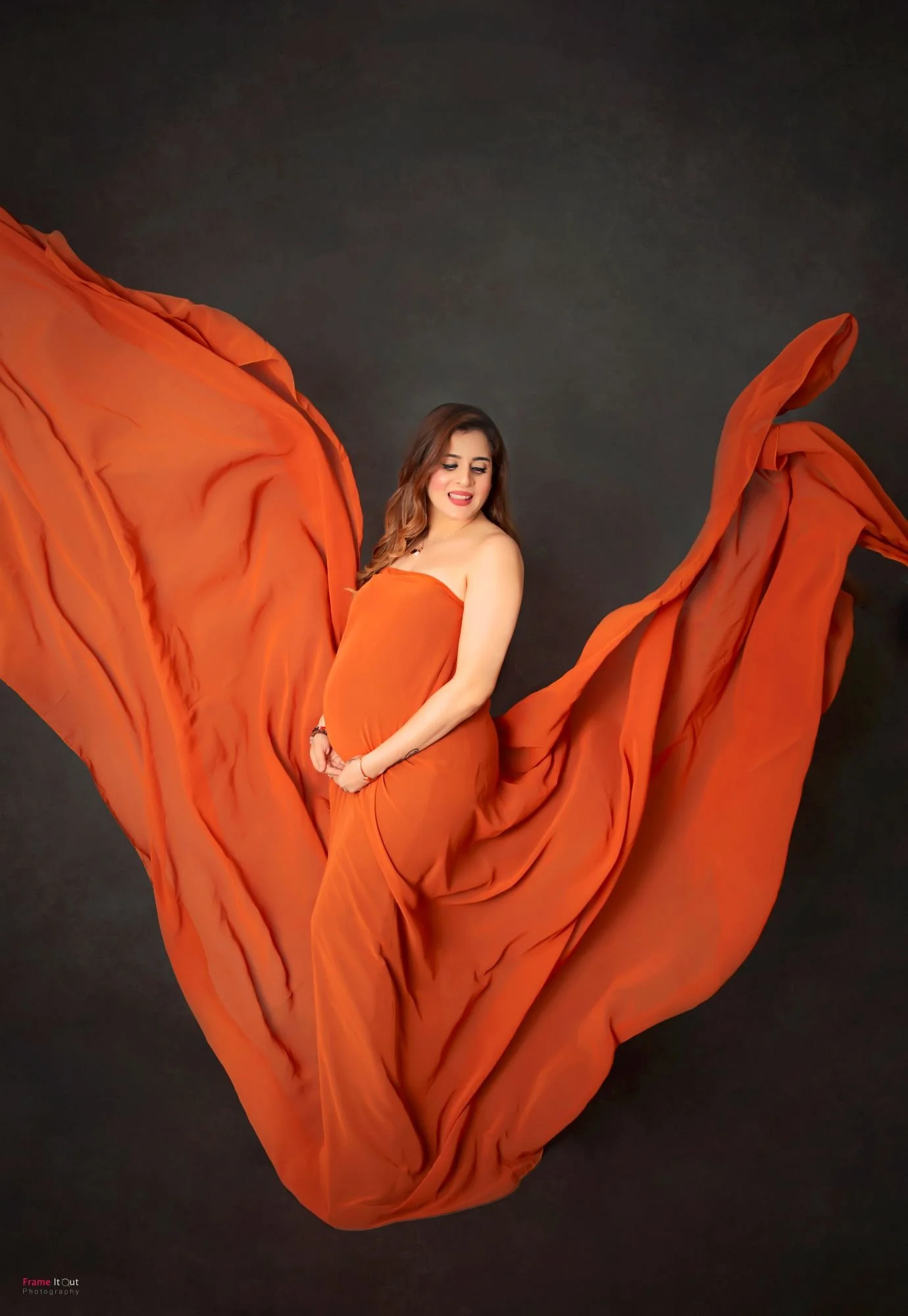 Fine-art maternity silhouette of pregnant woman in flowing gown