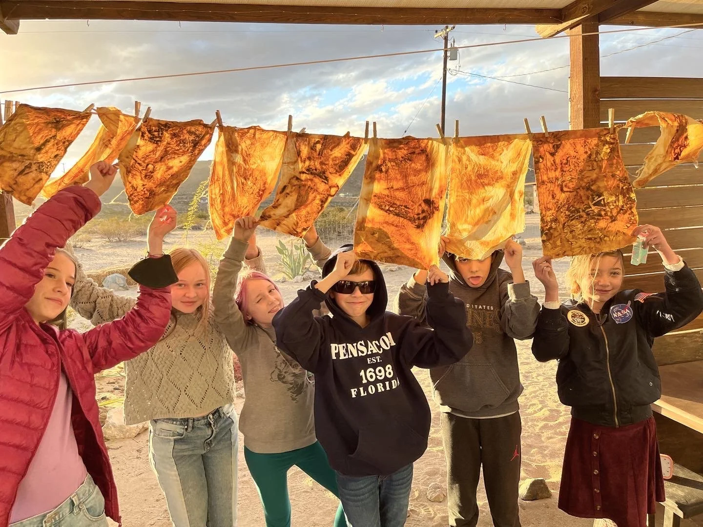 Students showing off found-object natural dye projects, using rusted desert items and vinegar, 2023.
