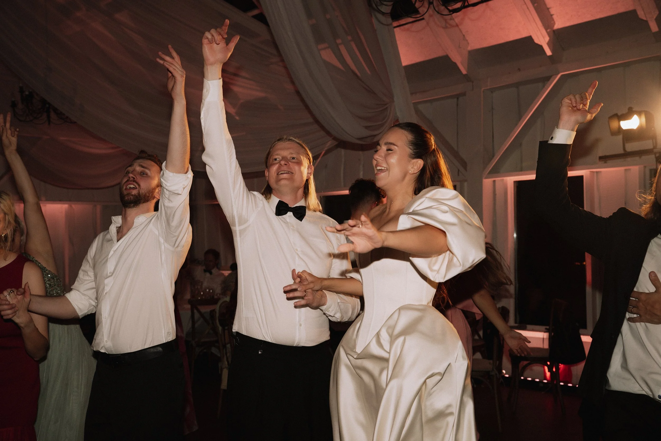 People dancing and celebrating at an event, some with arms raised and smiling.