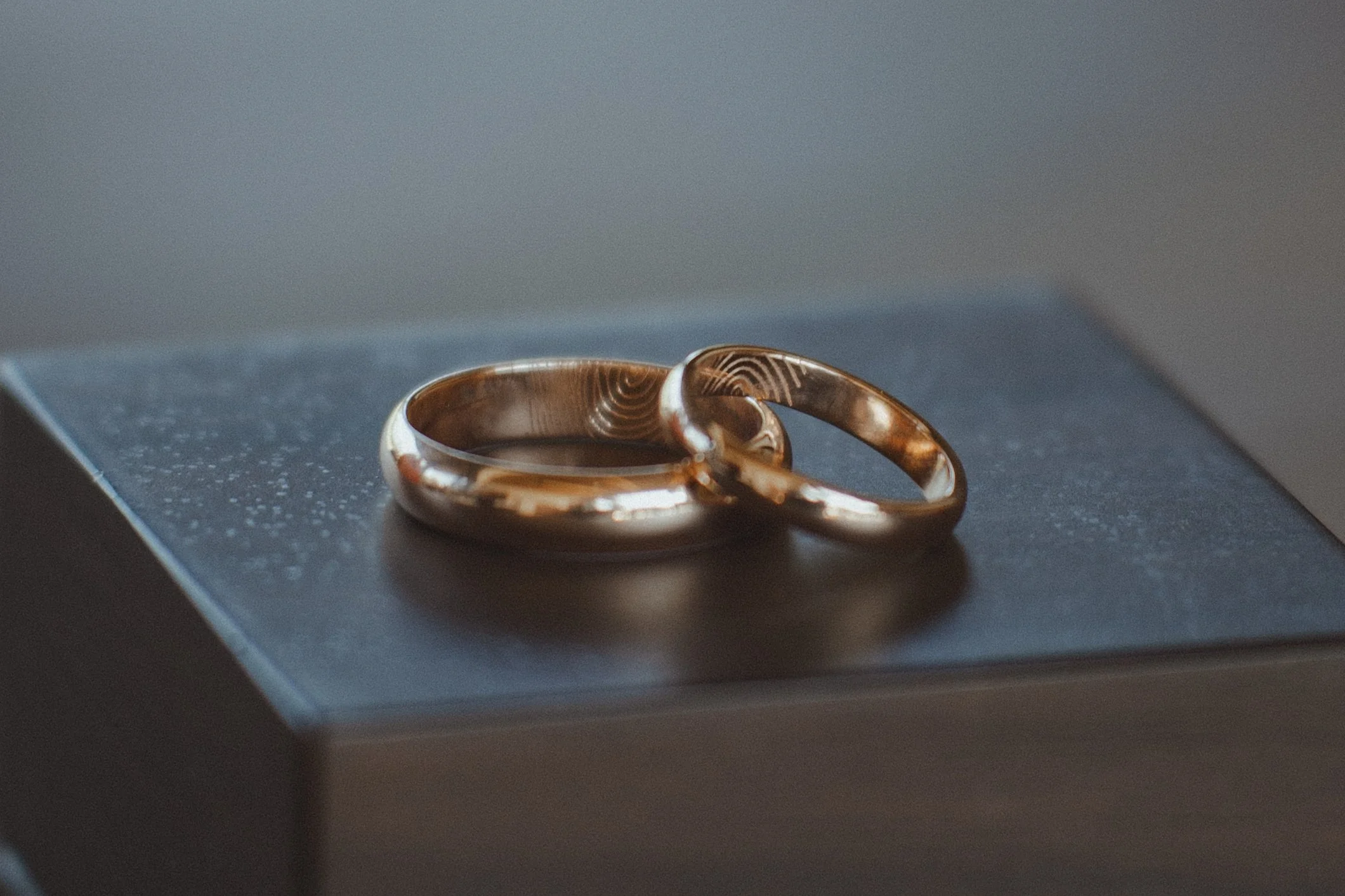 Two gold wedding rings resting on a black surface.
