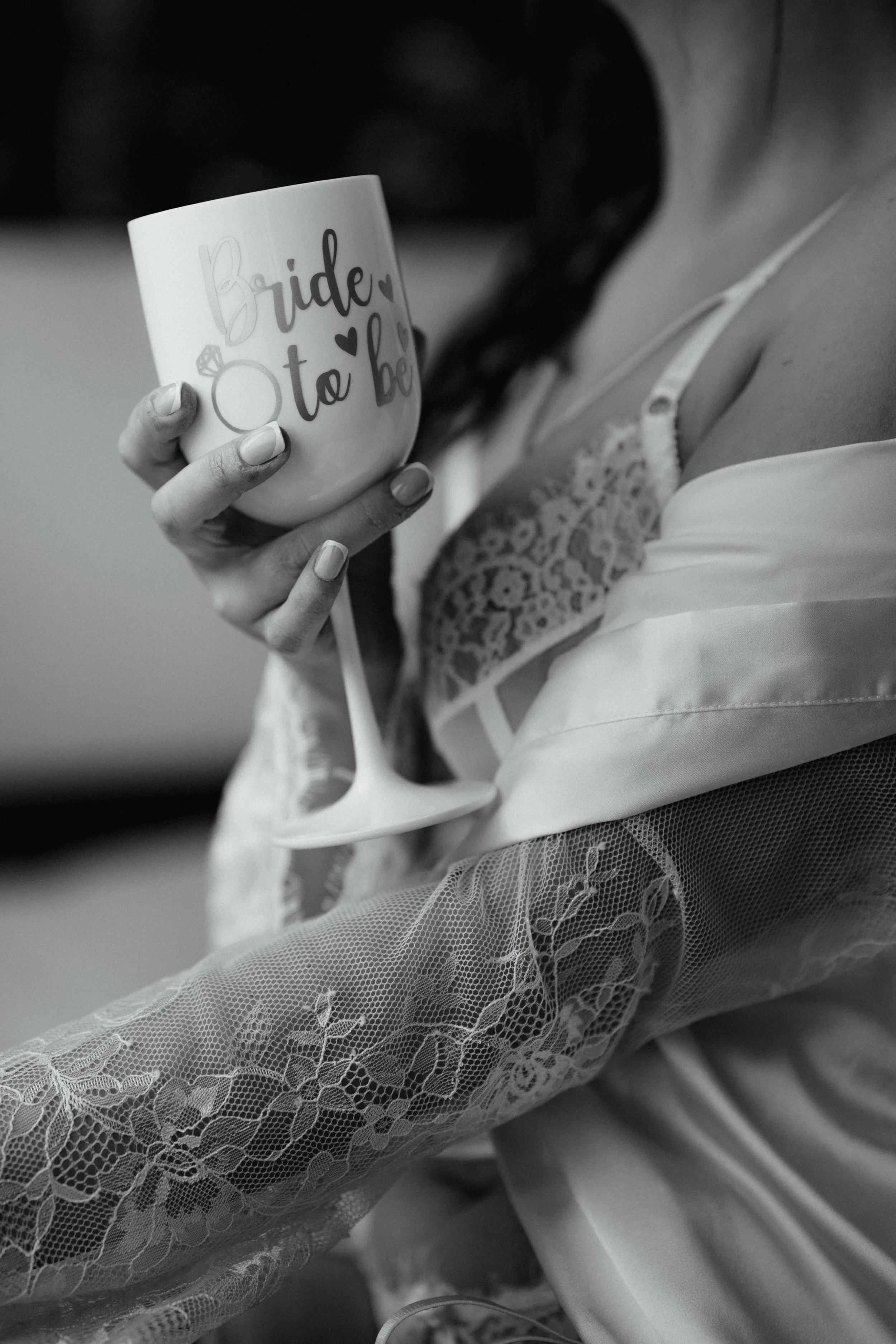 A woman in a wedding dress and lace sleeves holding a mug with the words 'Bride to be' written on it.