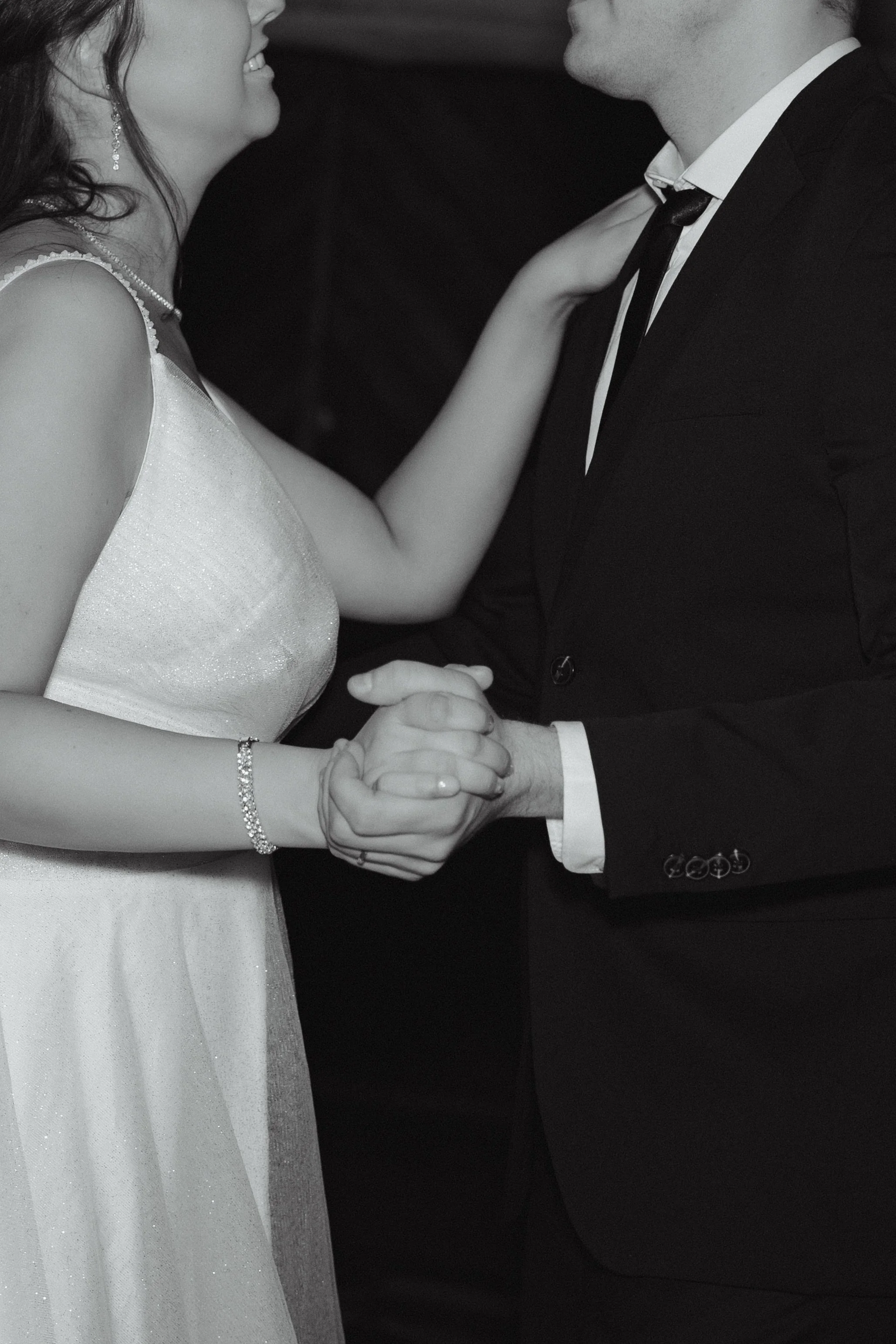 A couple dancing closely, holding hands, with their faces close together, at a formal event or wedding.