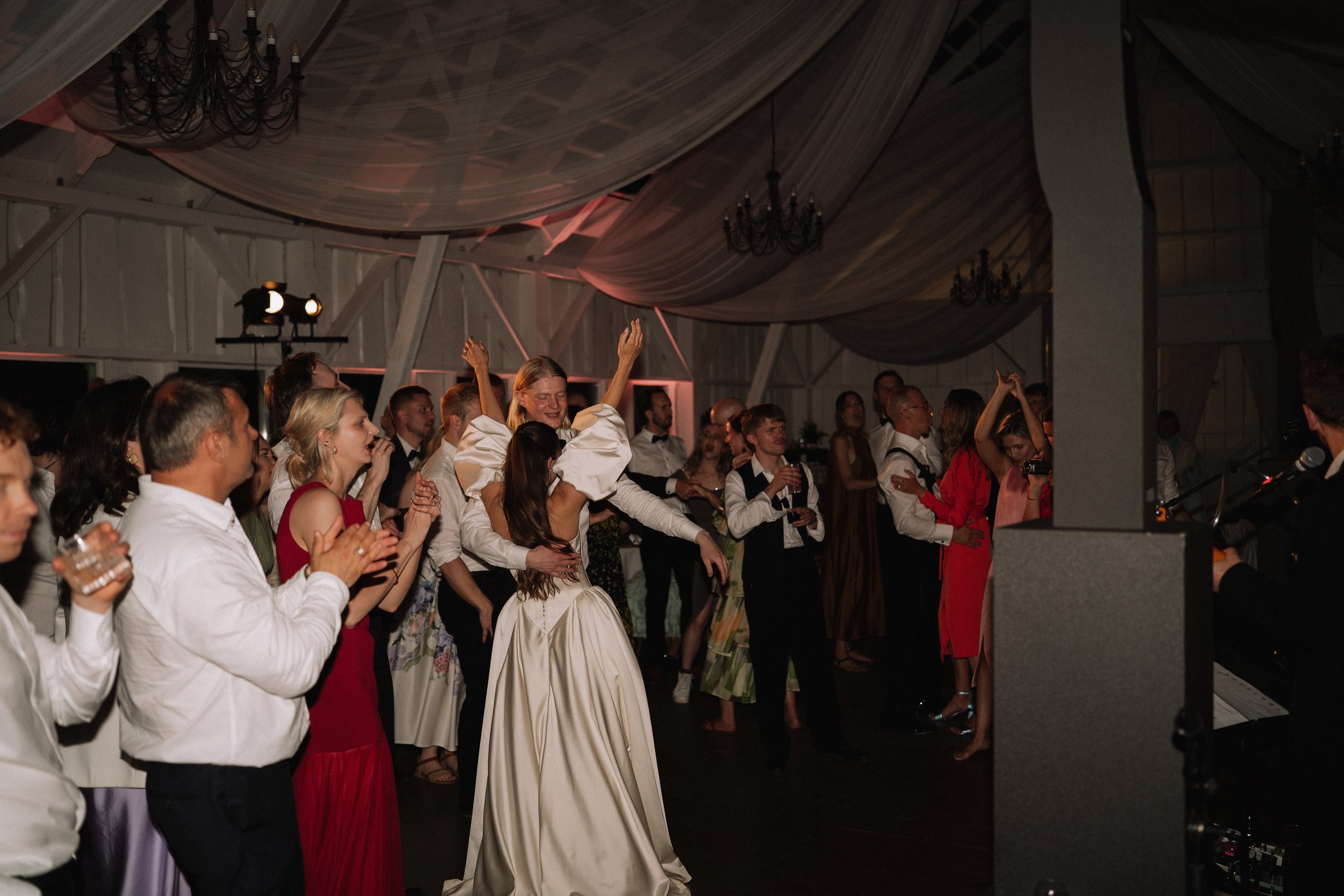 People dancing and enjoying music at a celebration or party in a decorated venue.