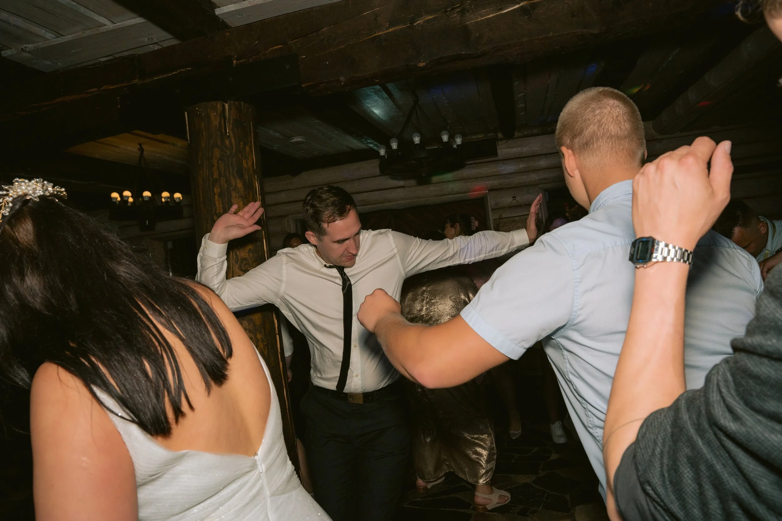 People dancing at a social gathering or party in a dimly lit indoor venue.