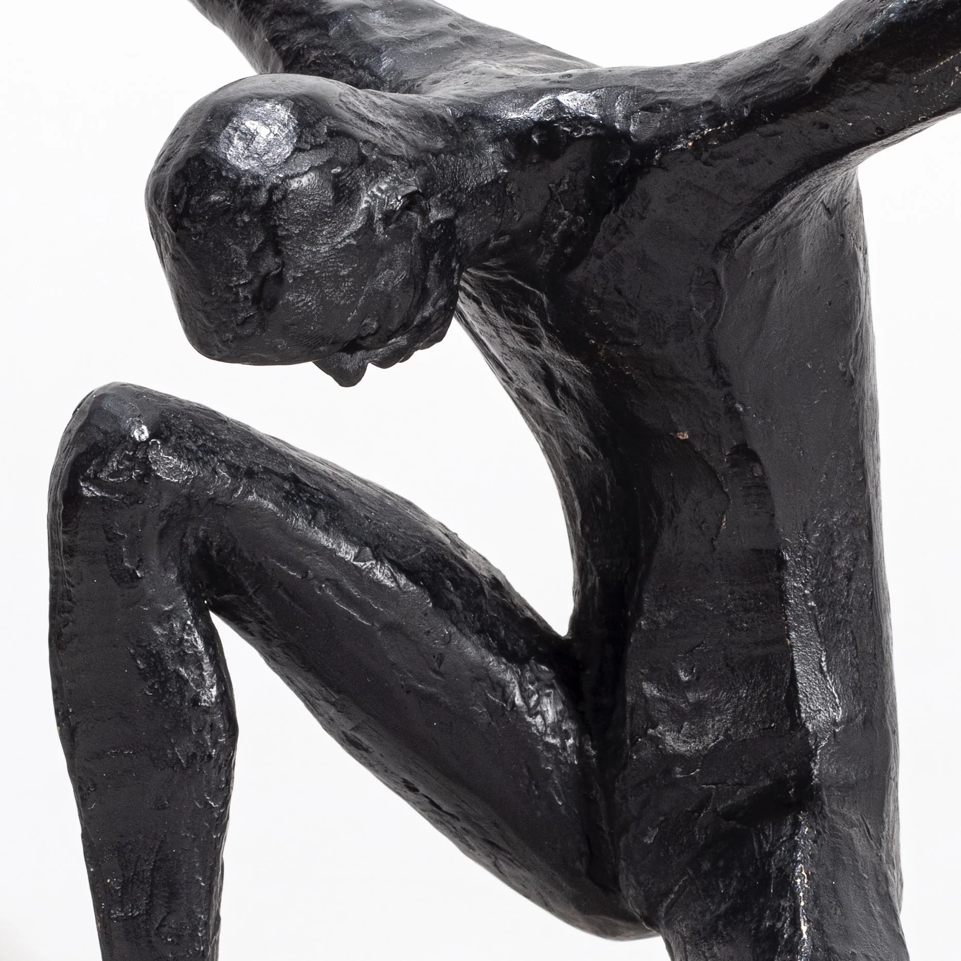 Close-up of a black, shiny, carved stone sculpture of an animal, possibly a dog or a fox, with a rounded head and elongated body, set against a white background.