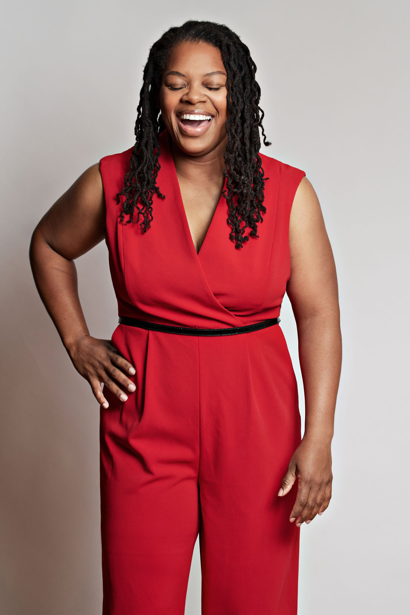 Editorial head shot of a woman in a red suit against a white background
