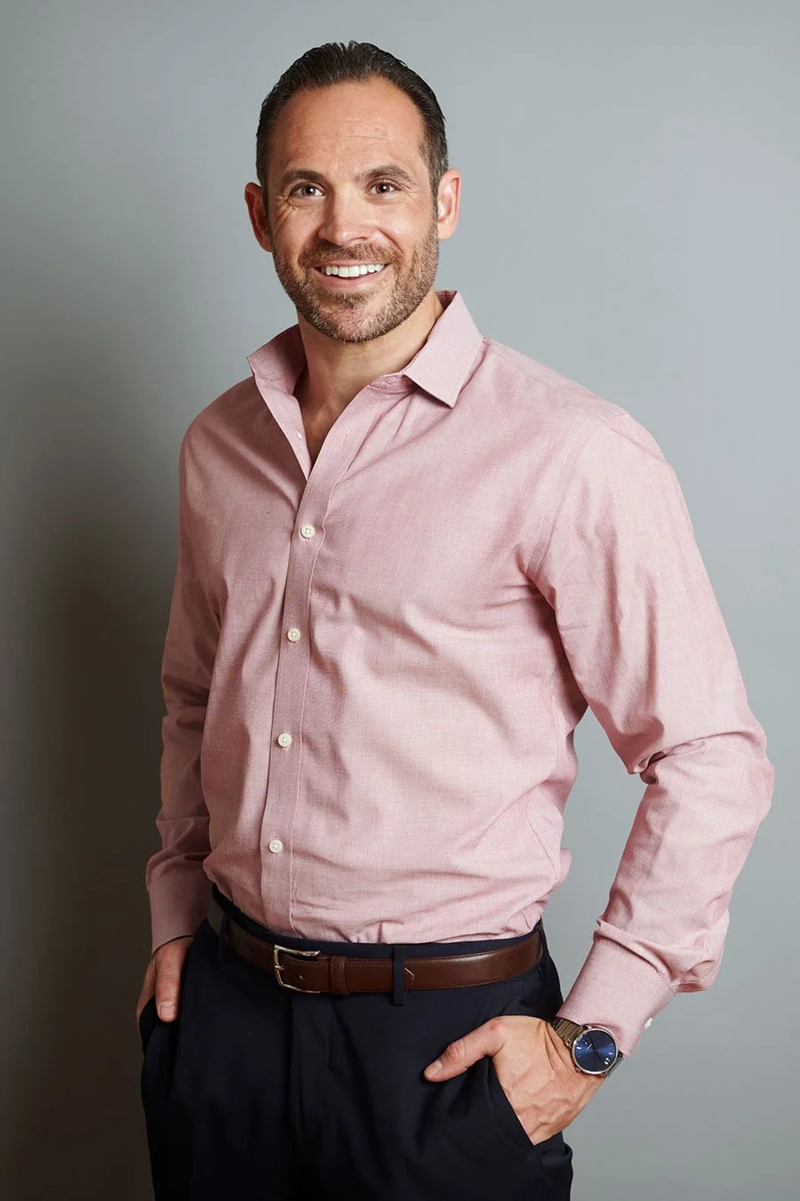portrait of a man against a gray background wearing a button down shirt. Business casual portrait.