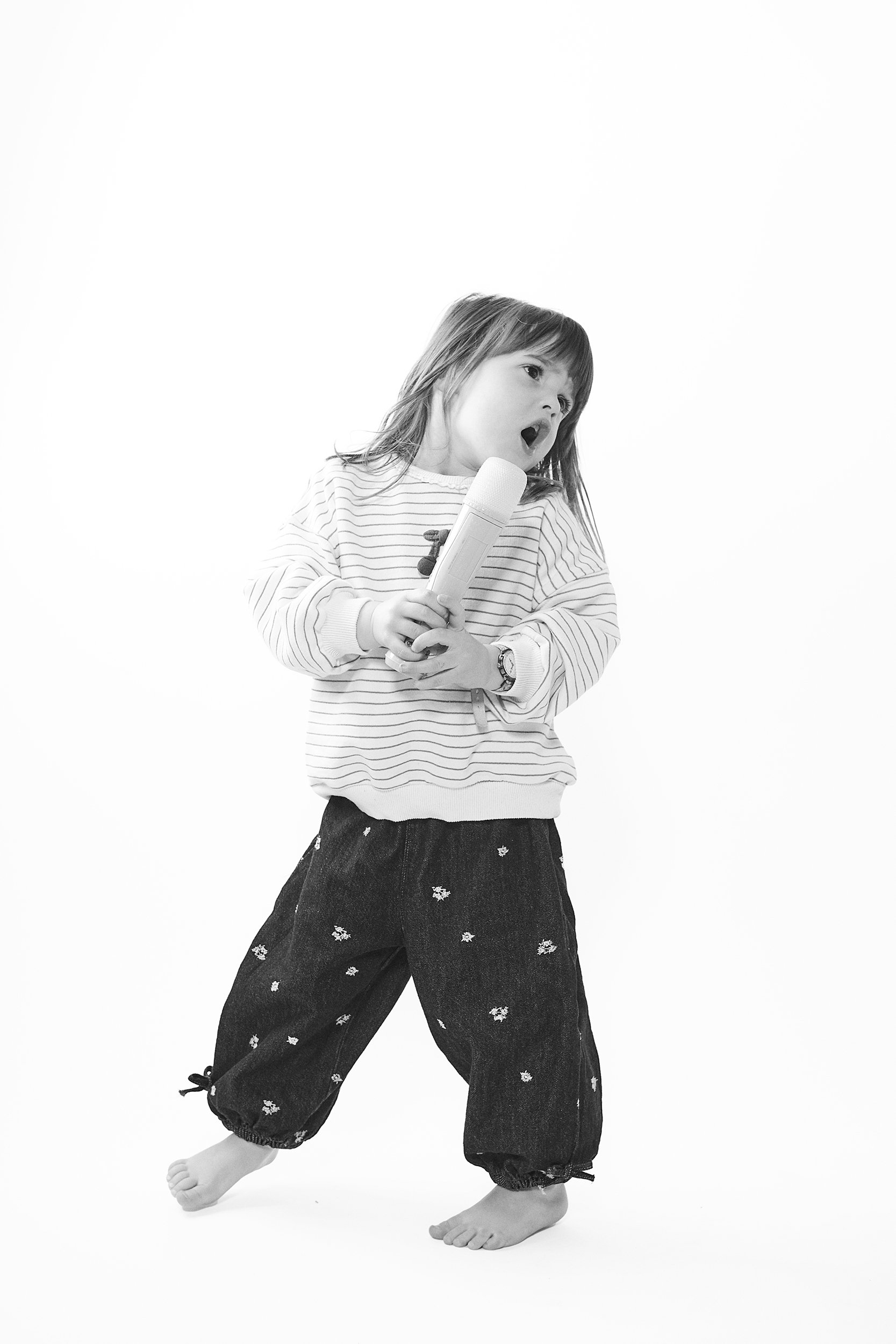 little girl emotionally singing into a fake microphone. black and white image on white background. portsmouth NH